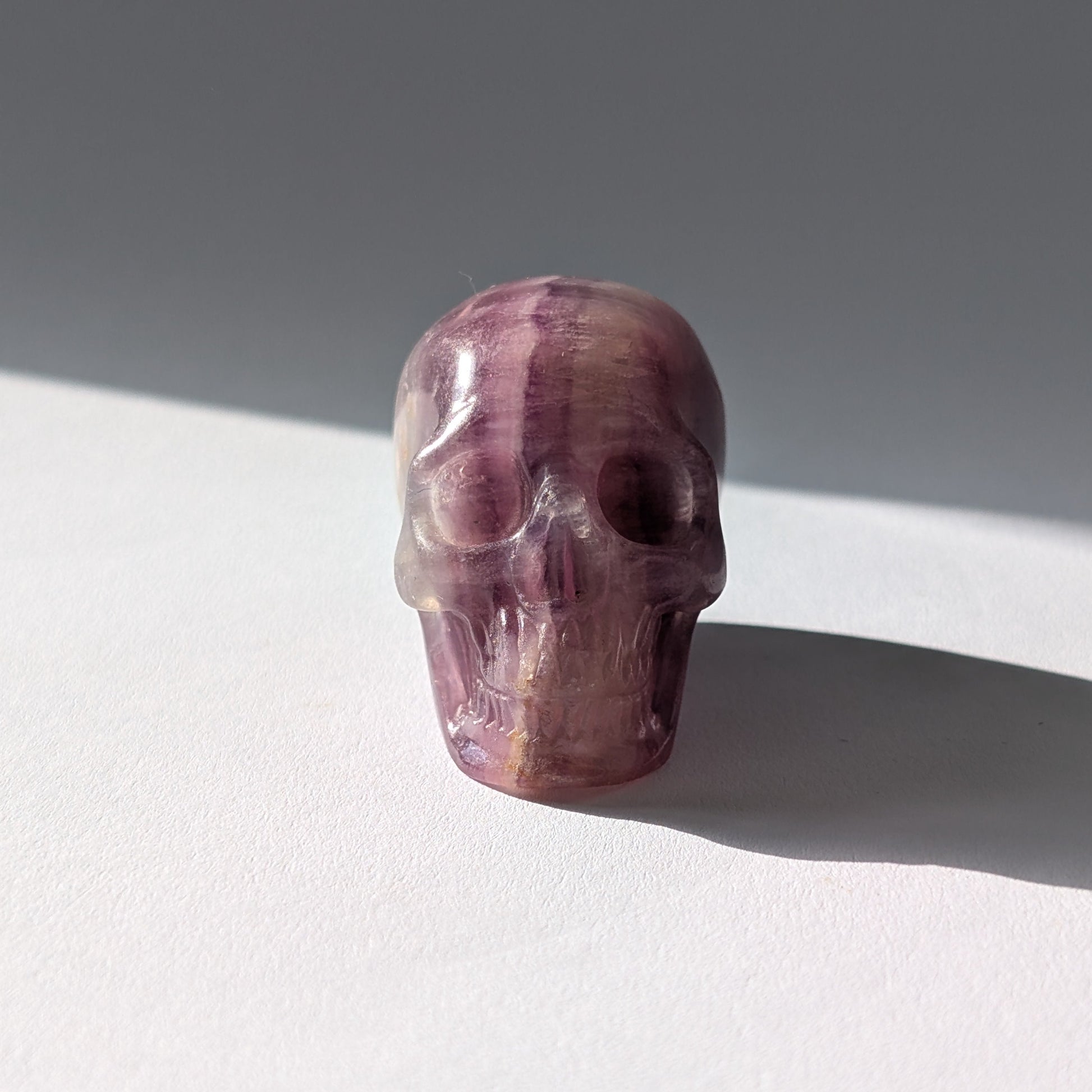 Kleiner Kristallschädel "Boron" (99g) aus klar gebändertem violett-weißem Fluorit.