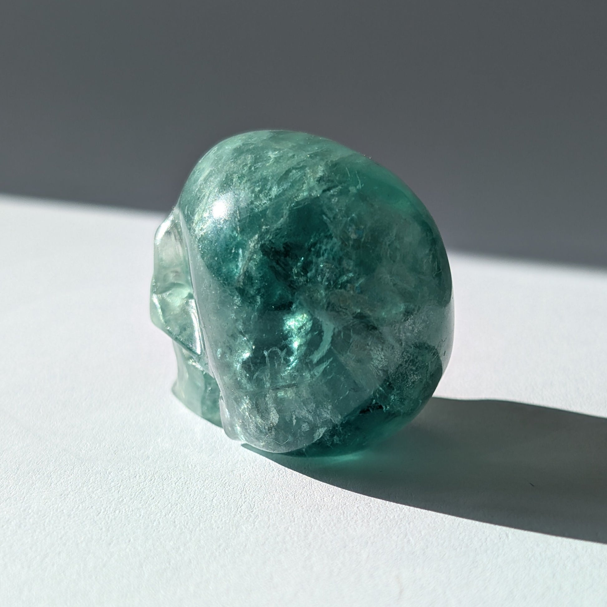 Kleiner Kristallschädel "Buros" (98g) aus klar gebändertem violett-weißem Fluorit.