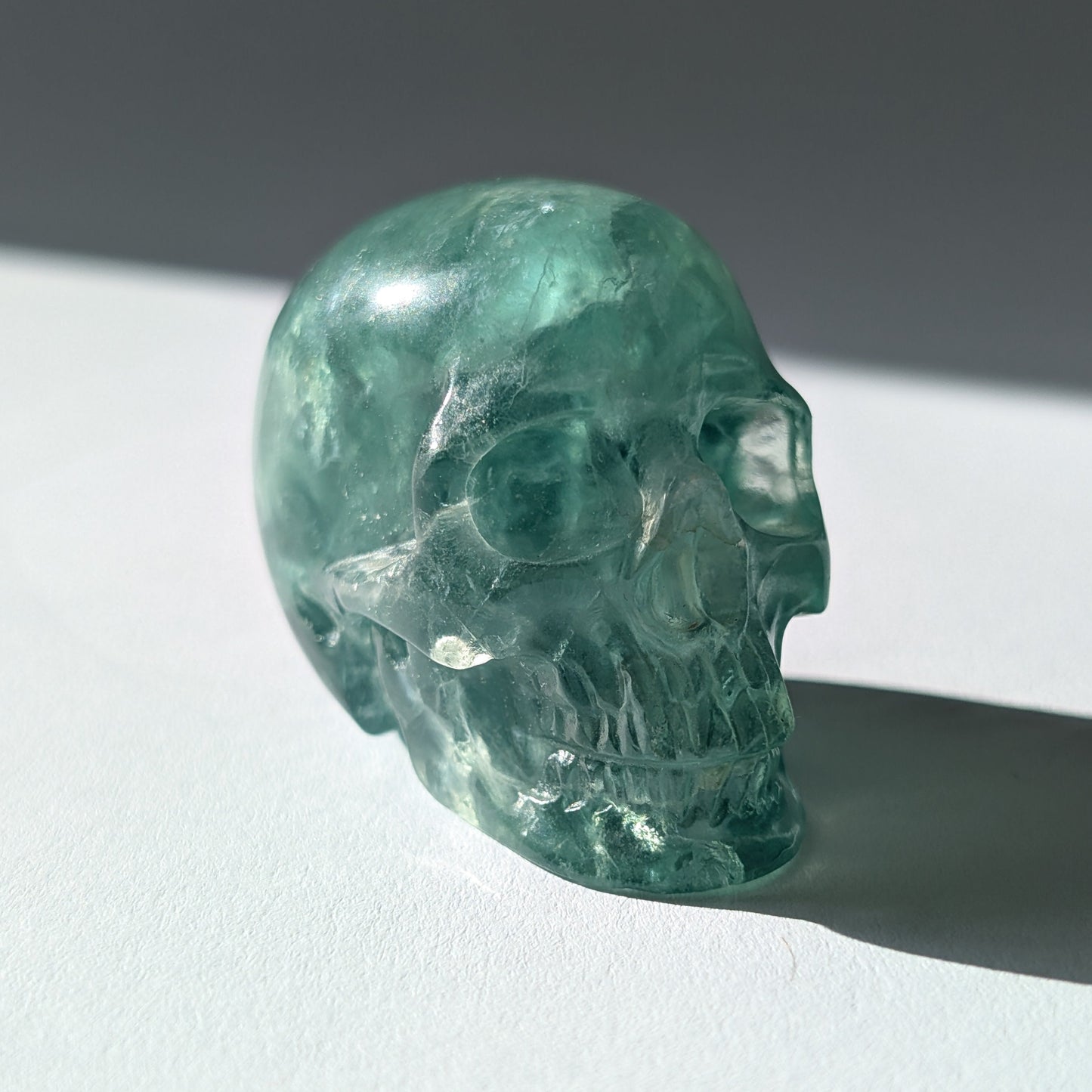 Kleiner Kristallschädel "Buros" (98g) aus klar gebändertem violett-weißem Fluorit.