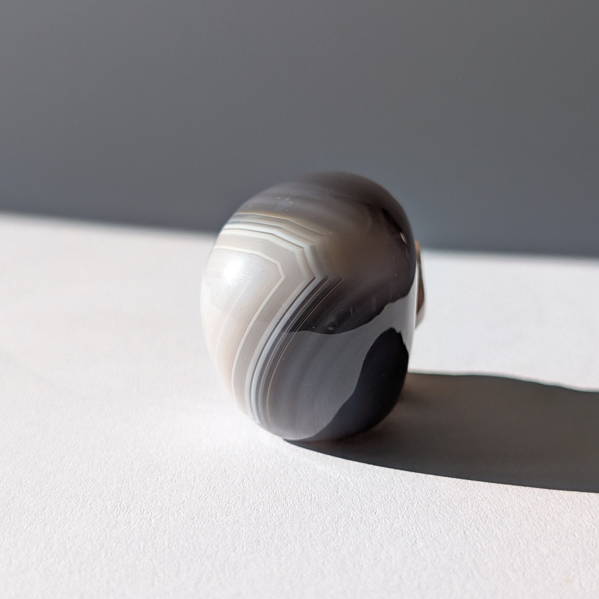 Kleiner Kristallschädel "Colan" (85g) aus grau-weiß gebändertem Botswana Achat.