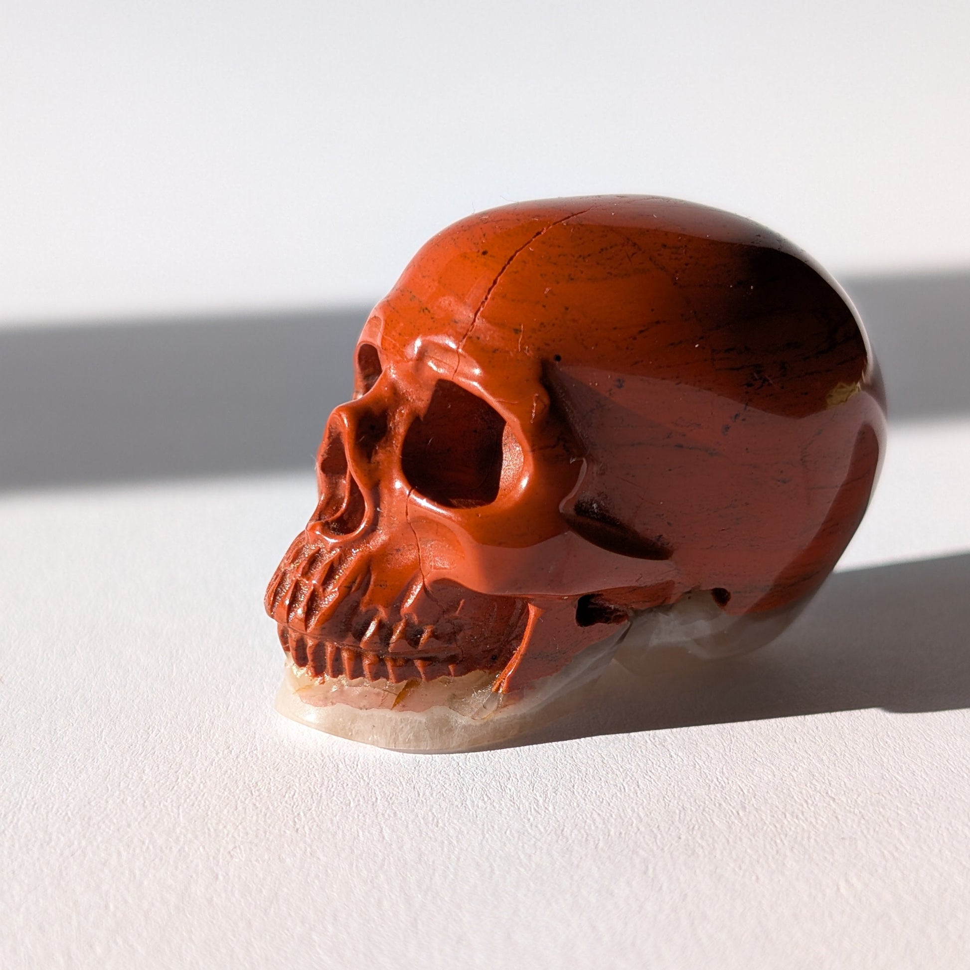 Kleiner Kristallschädel "Edun" (86g), halb aus rotem Jaspis, halb aus hellem Quarz.