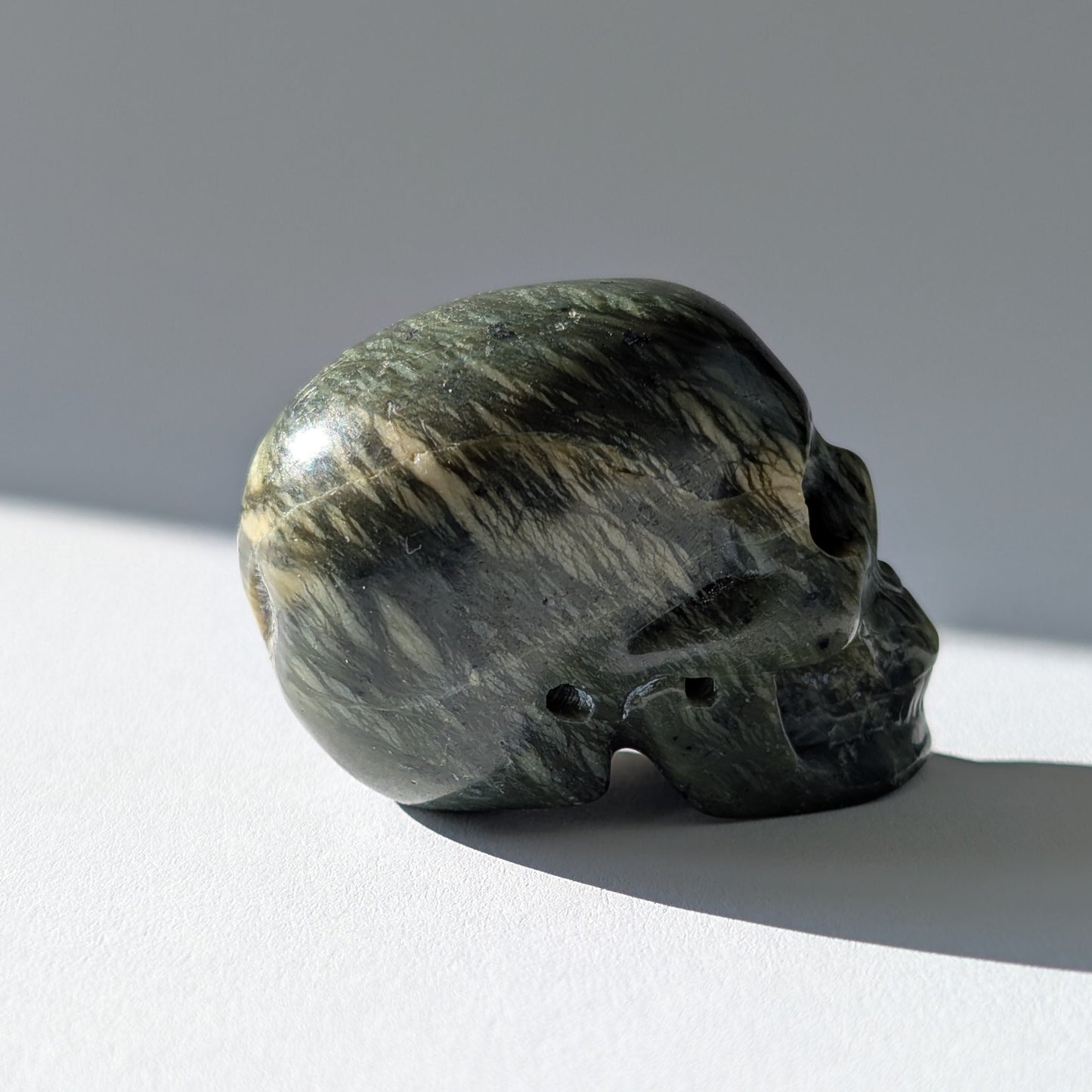 Kleiner Kristallschädel "Obak" (78g) aus dunkelgrün gemustertem Serpentin.