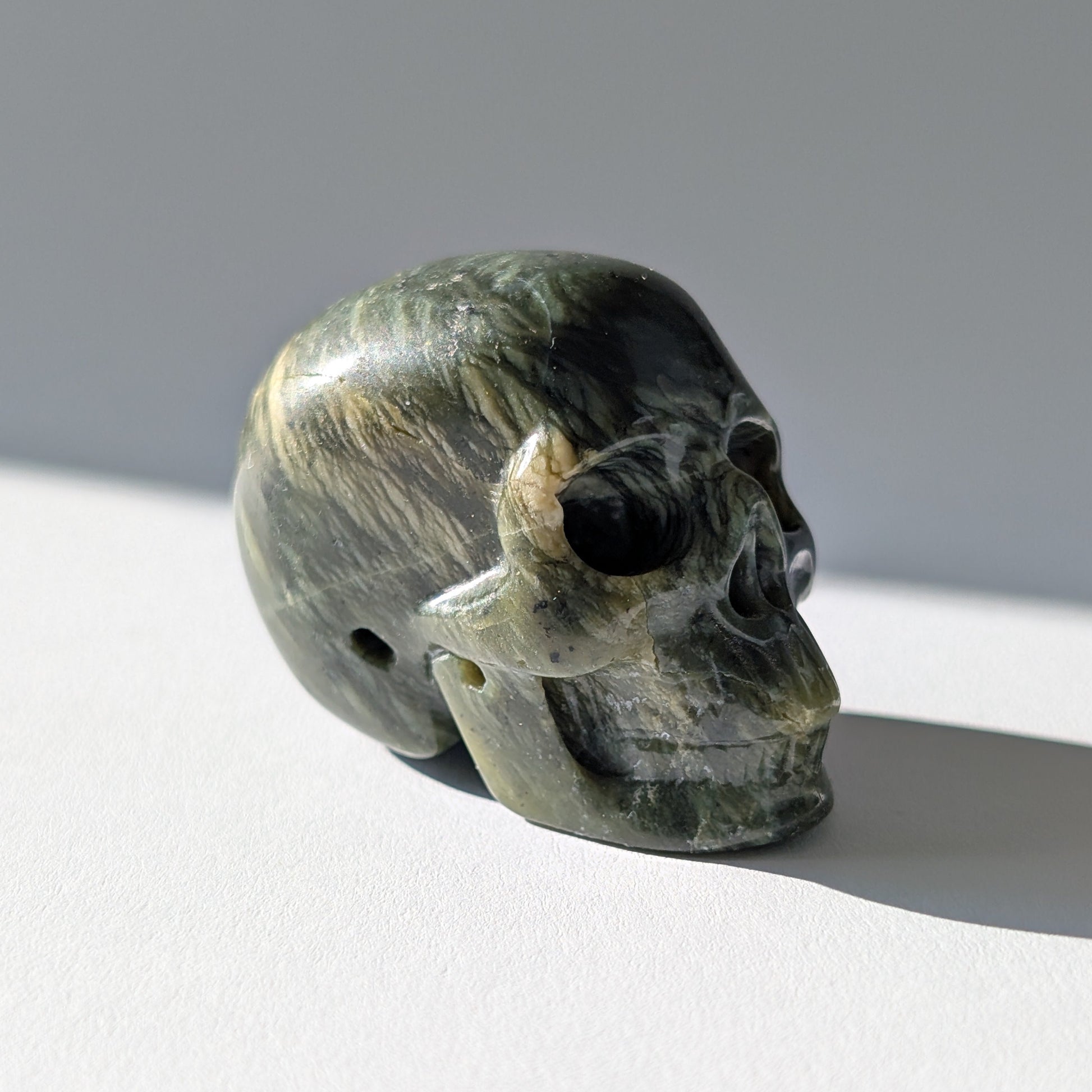 Kleiner Kristallschädel "Obak" (78g) aus dunkelgrün gemustertem Serpentin.