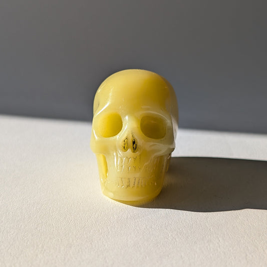 Kleiner Kristallschädel "Sentos" (78g) aus blassgrün-gelbem Jadeit im Licht.