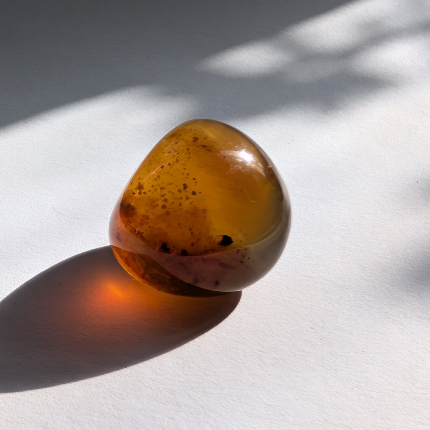 Kleiner, ergonomischer Bicolor-Bernstein 'Der goldene Funke' mit juwelenartiger Klarheit und einem Farbverlauf von Cognac zu Gold.