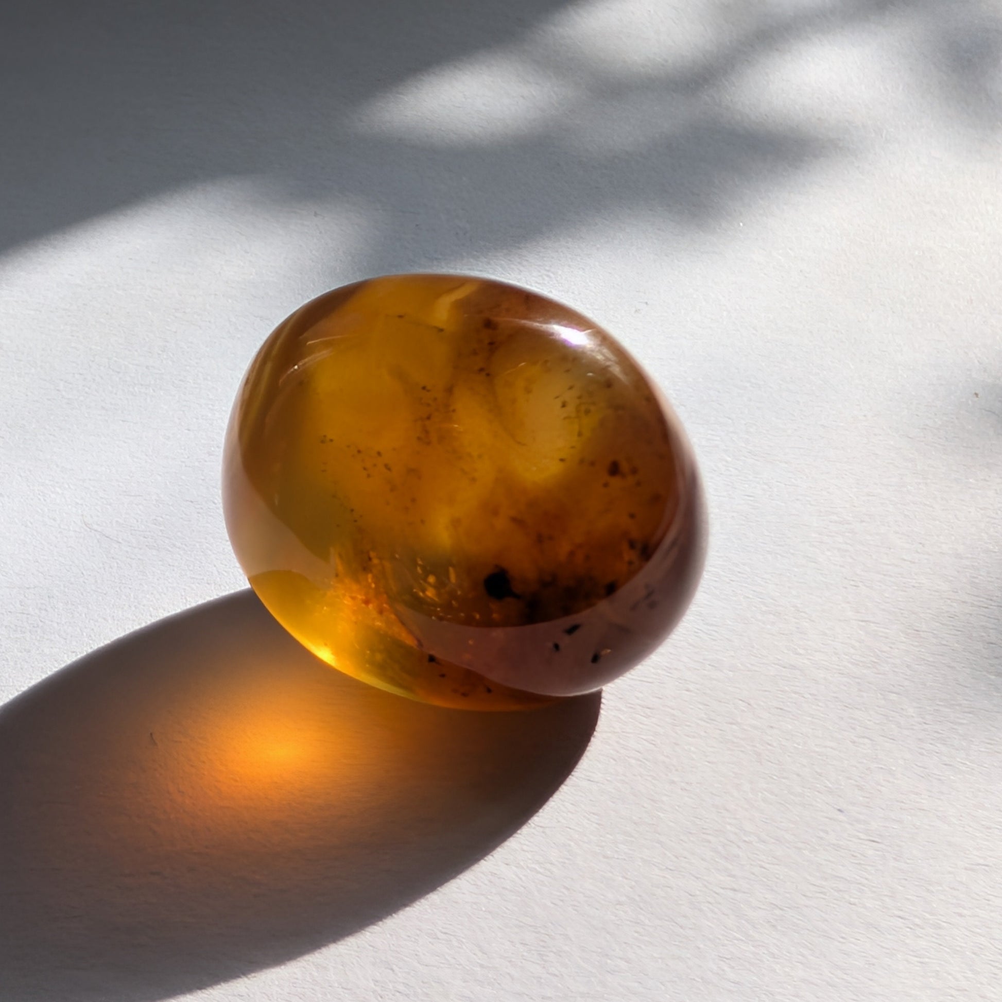Kleiner, ergonomischer Bicolor-Bernstein 'Der goldene Funke' mit juwelenartiger Klarheit und einem Farbverlauf von Cognac zu Gold.