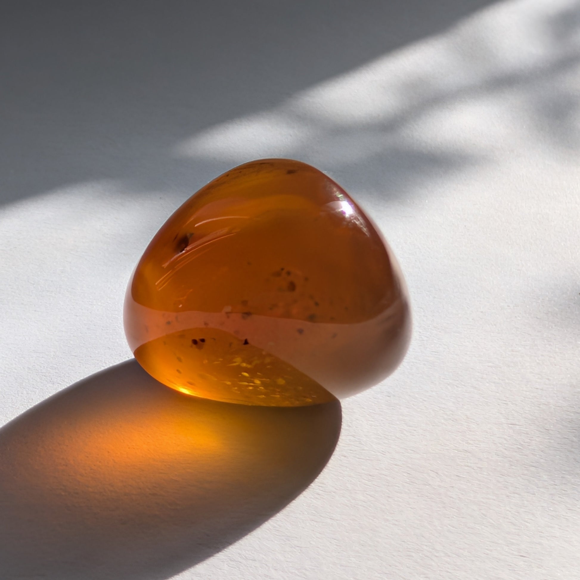 Kleiner, ergonomischer Bicolor-Bernstein 'Der goldene Funke' mit juwelenartiger Klarheit und einem Farbverlauf von Cognac zu Gold.