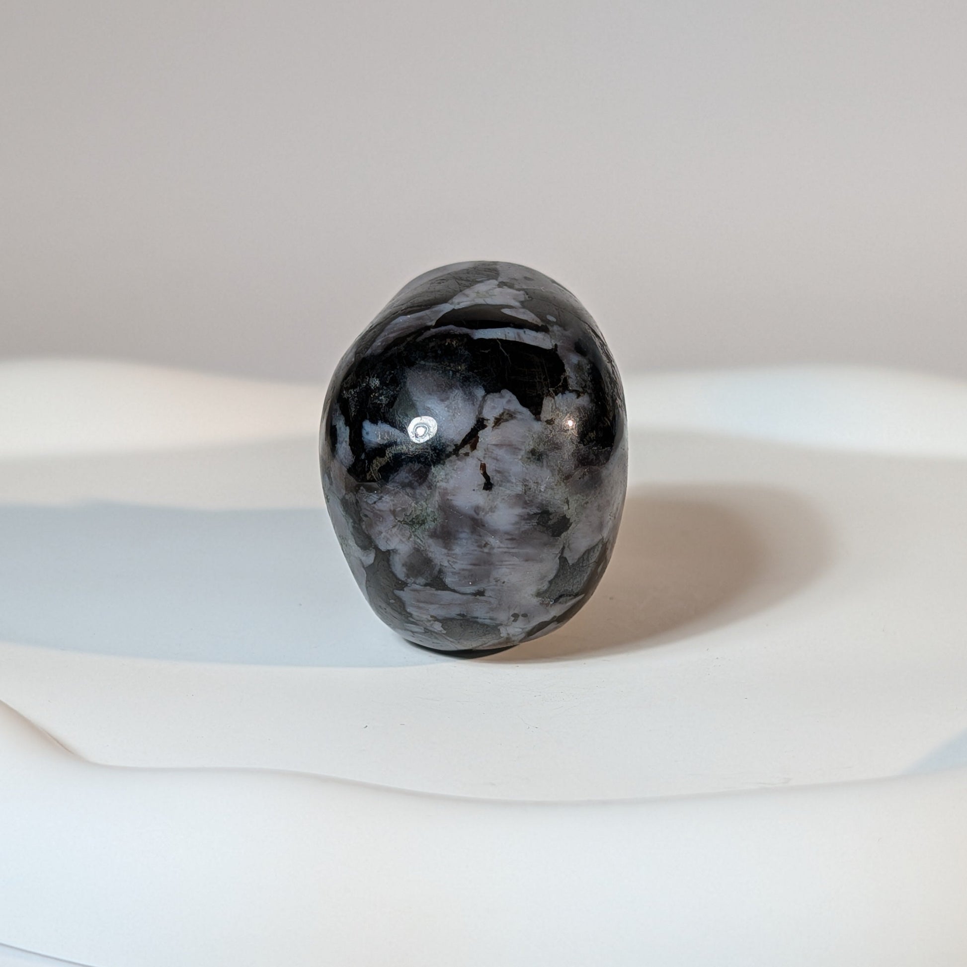 Kompakter Kristallschädel Fayt aus Nephelin, mit einer hellen, von dunklen Mineralien gesprenkelten Gesteinsmatrix.