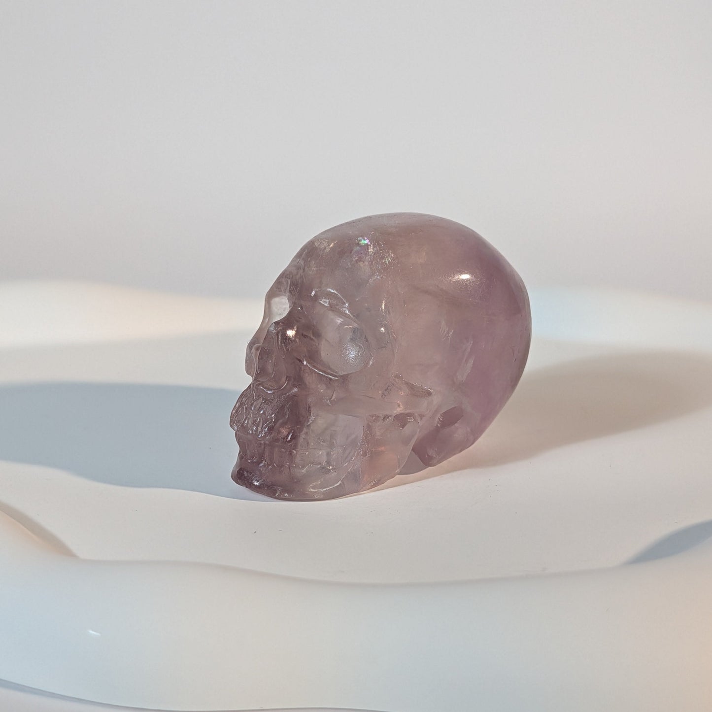 Kompakter Kristallschädel Vandarr aus durchscheinendem, violettem Fluorit mit rauer, körniger Lichtwirkung und tiefen Schatten.