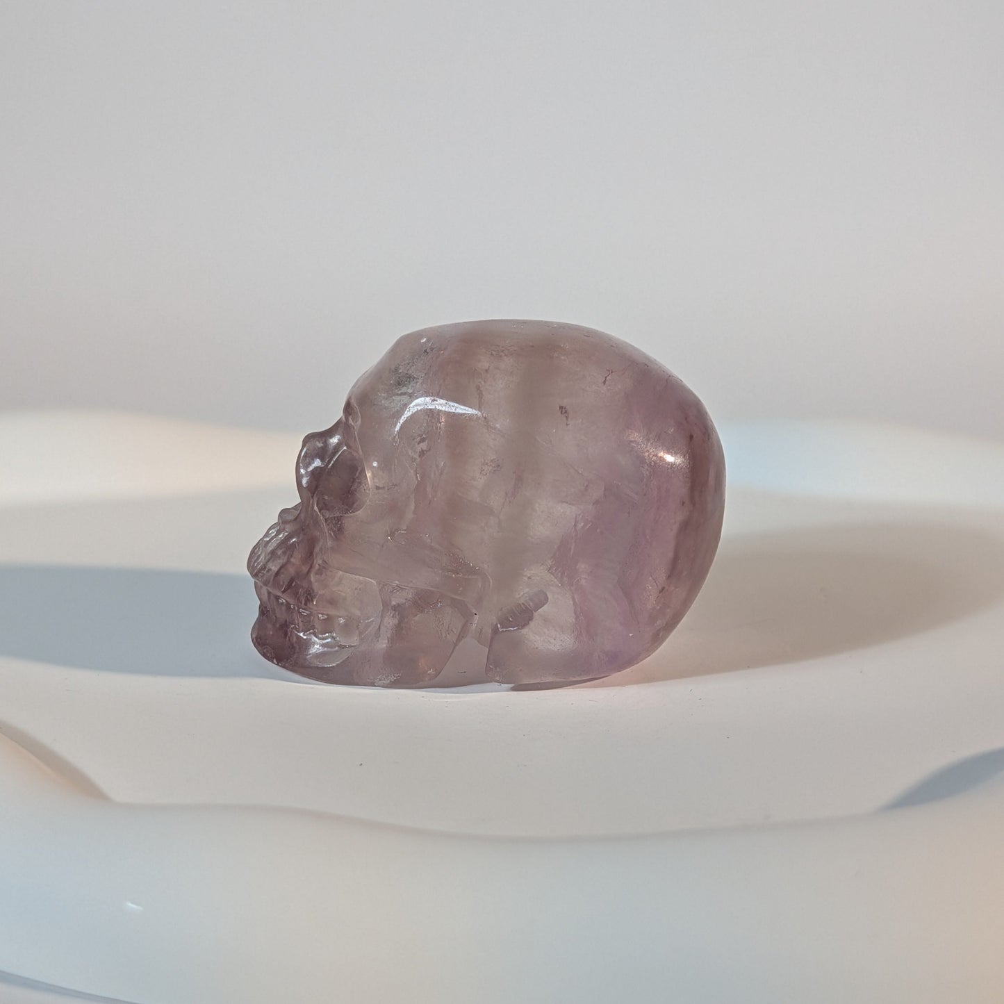 Kompakter Kristallschädel Vandarr aus durchscheinendem, violettem Fluorit mit rauer, körniger Lichtwirkung und tiefen Schatten.