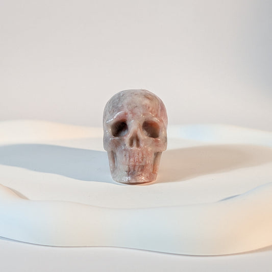 Kristallschädel Armun aus rohem Klinozoisit 92g mit dunklen, natürlichen Einschlüssen und harten Brüchen im kontrastreichen Licht