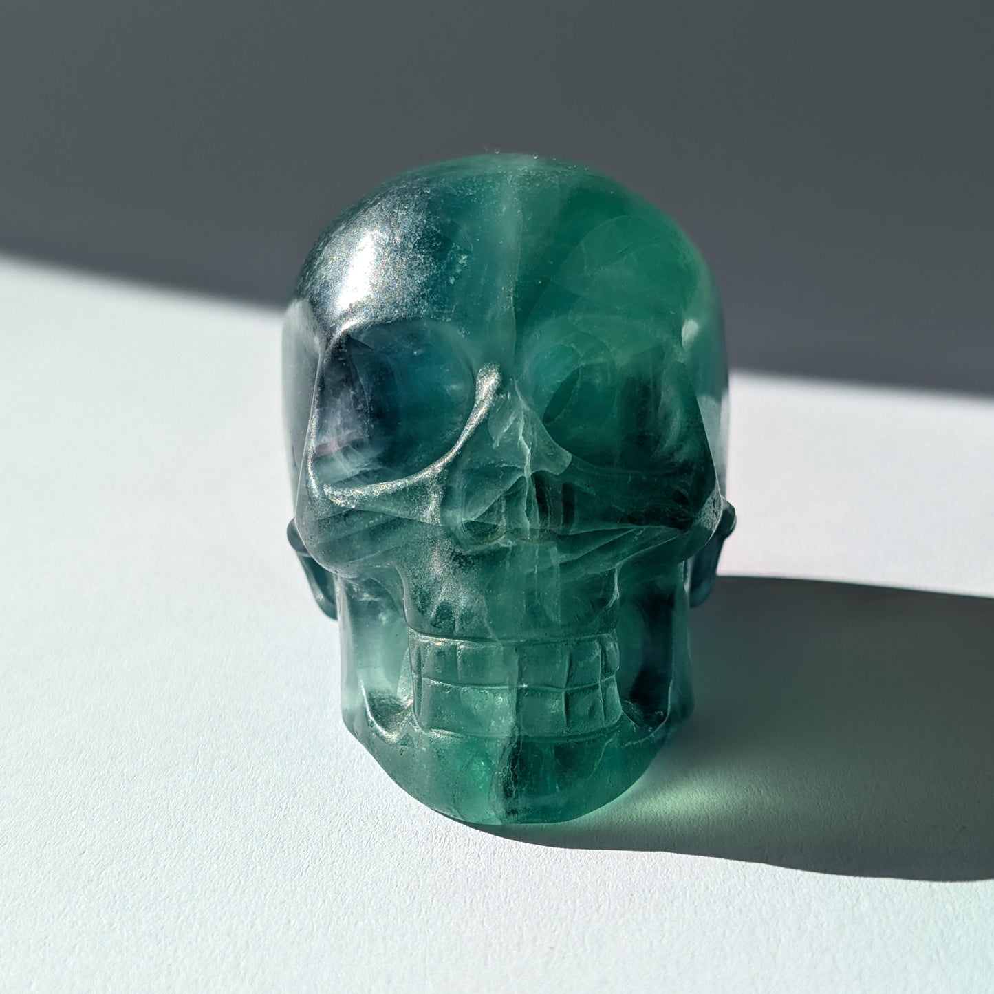 Kristallschädel "Guilin" (338g) aus leuchtend grünem, klarem Fluorit im Licht.