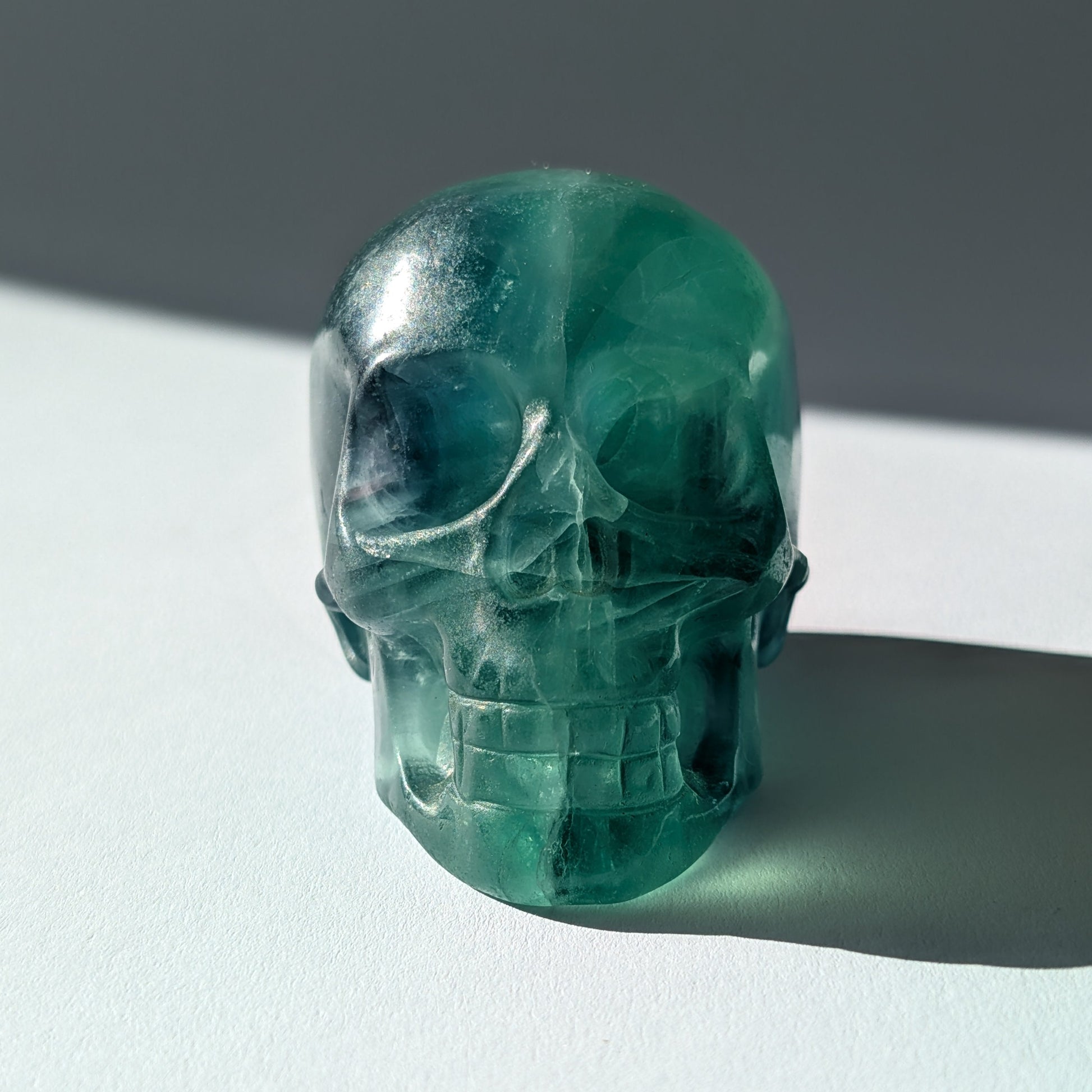 Kristallschädel "Guilin" (338g) aus leuchtend grünem, klarem Fluorit im Licht.