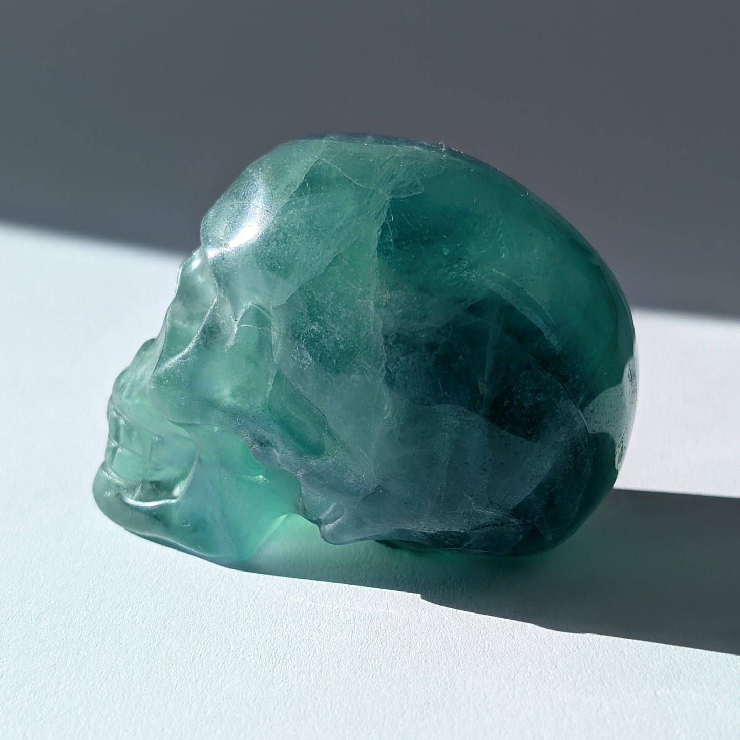 Kristallschädel "Guilin" (338g) aus leuchtend grünem, klarem Fluorit im Licht.