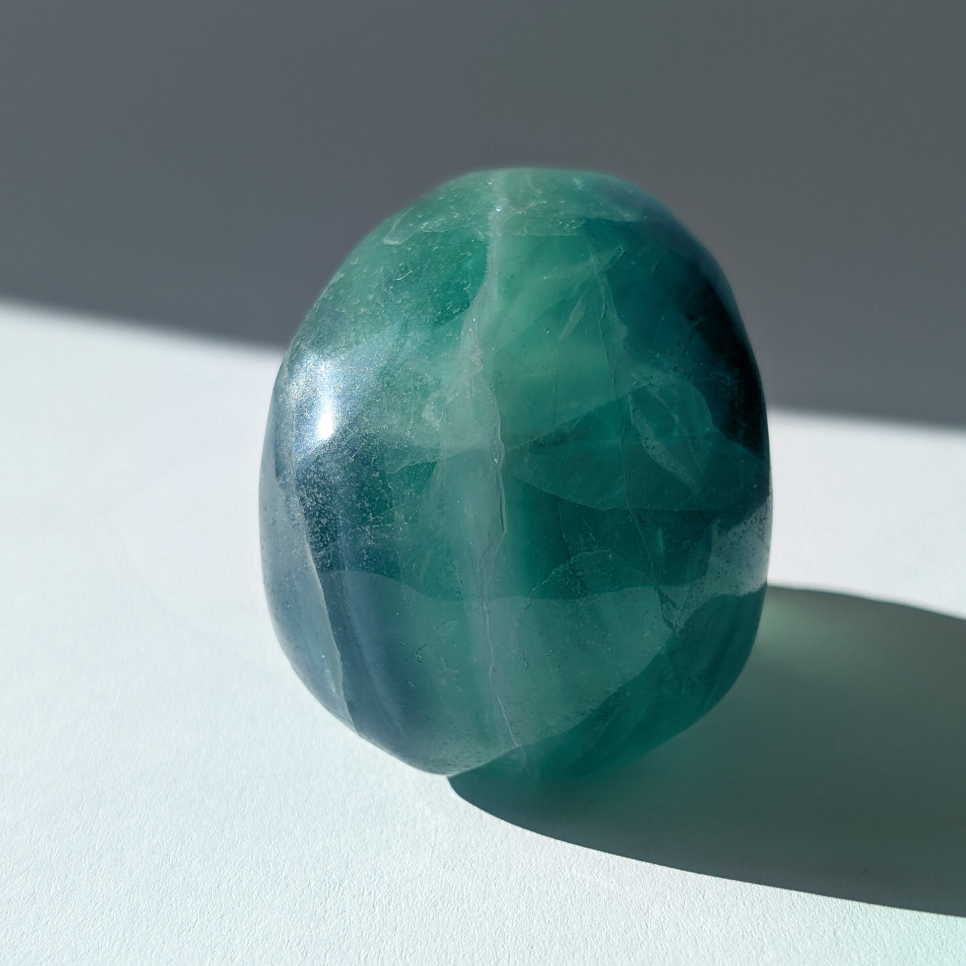 Kristallschädel "Guilin" (338g) aus leuchtend grünem, klarem Fluorit im Licht.