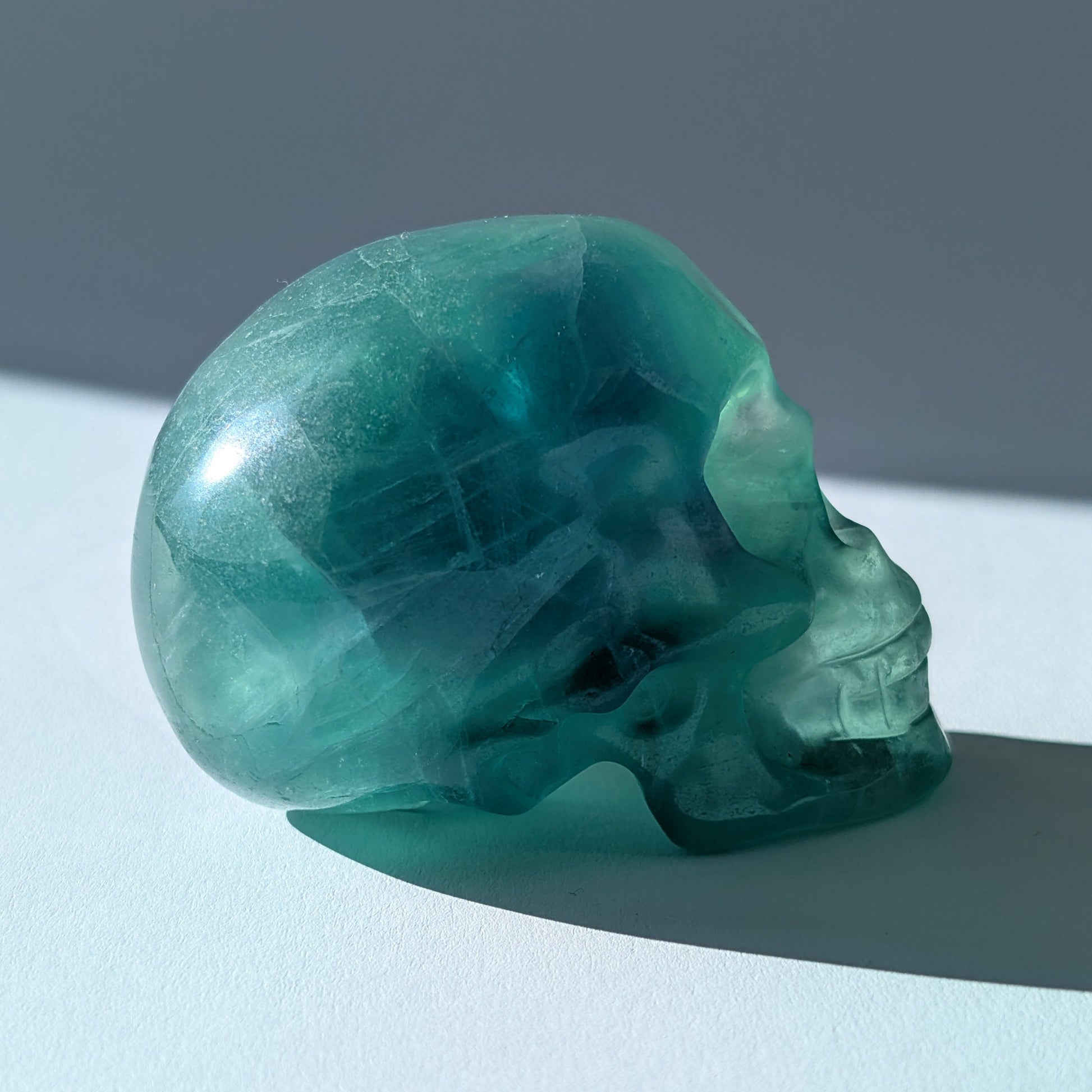 Kristallschädel "Guilin" (338g) aus leuchtend grünem, klarem Fluorit im Licht.