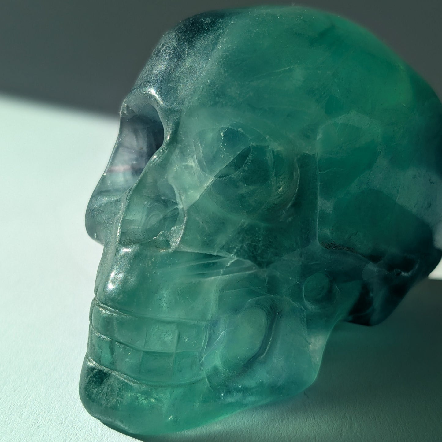 Kristallschädel "Guilin" (338g) aus leuchtend grünem, klarem Fluorit im Licht.