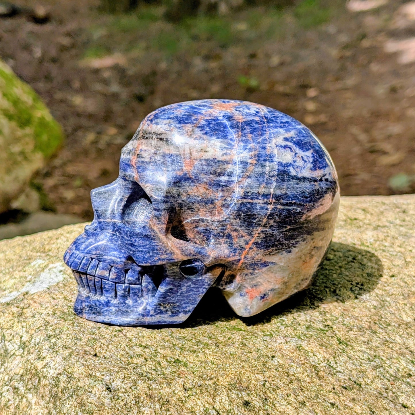 Kristallschädel "Himmelsweiser" aus Sodalith mit blau-weißer Maserung und orange-braunen Adern.