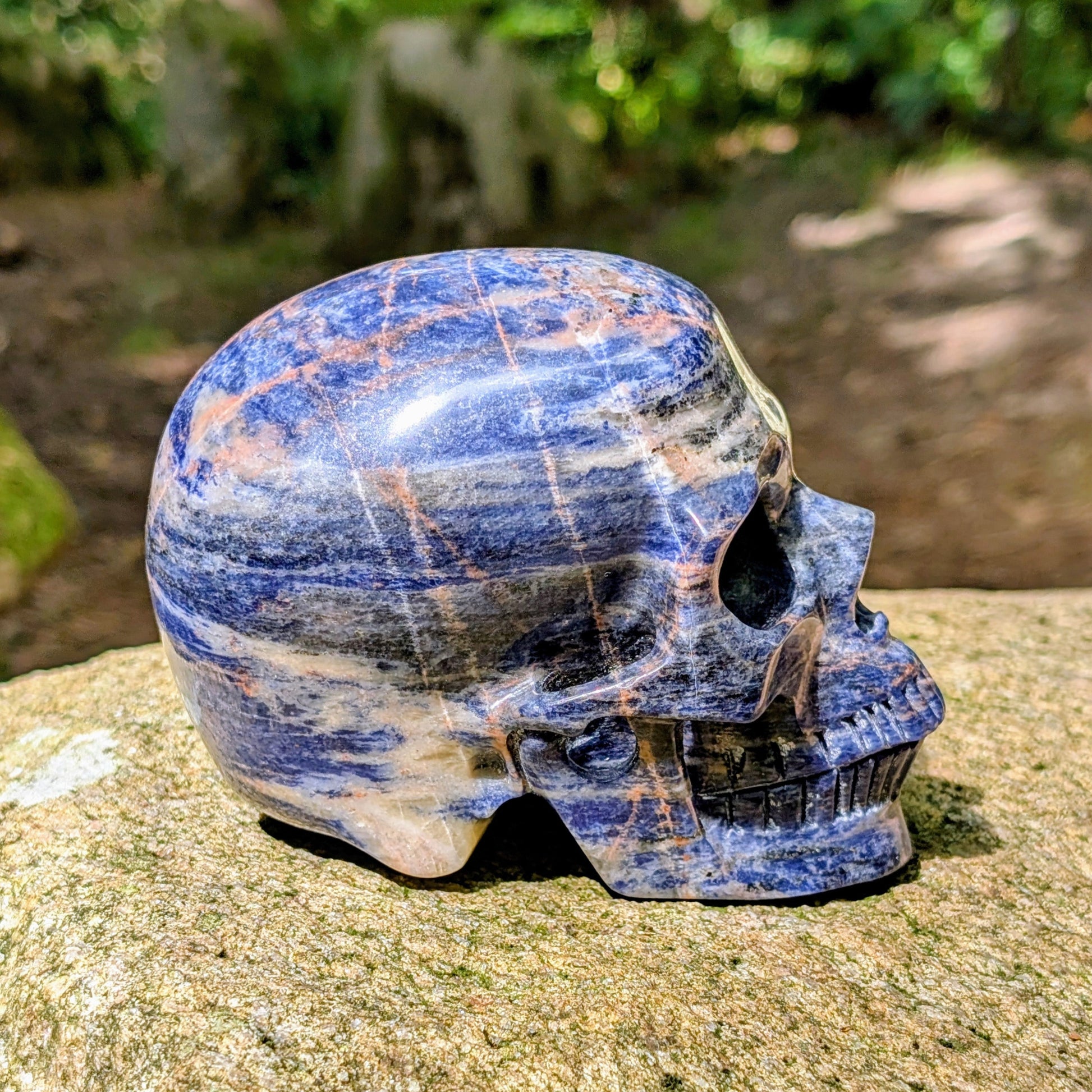 Kristallschädel "Himmelsweiser" aus Sodalith mit blau-weißer Maserung und orange-braunen Adern.