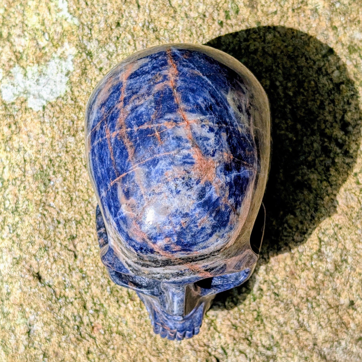 Kristallschädel "Himmelsweiser" aus Sodalith mit blau-weißer Maserung und orange-braunen Adern.
