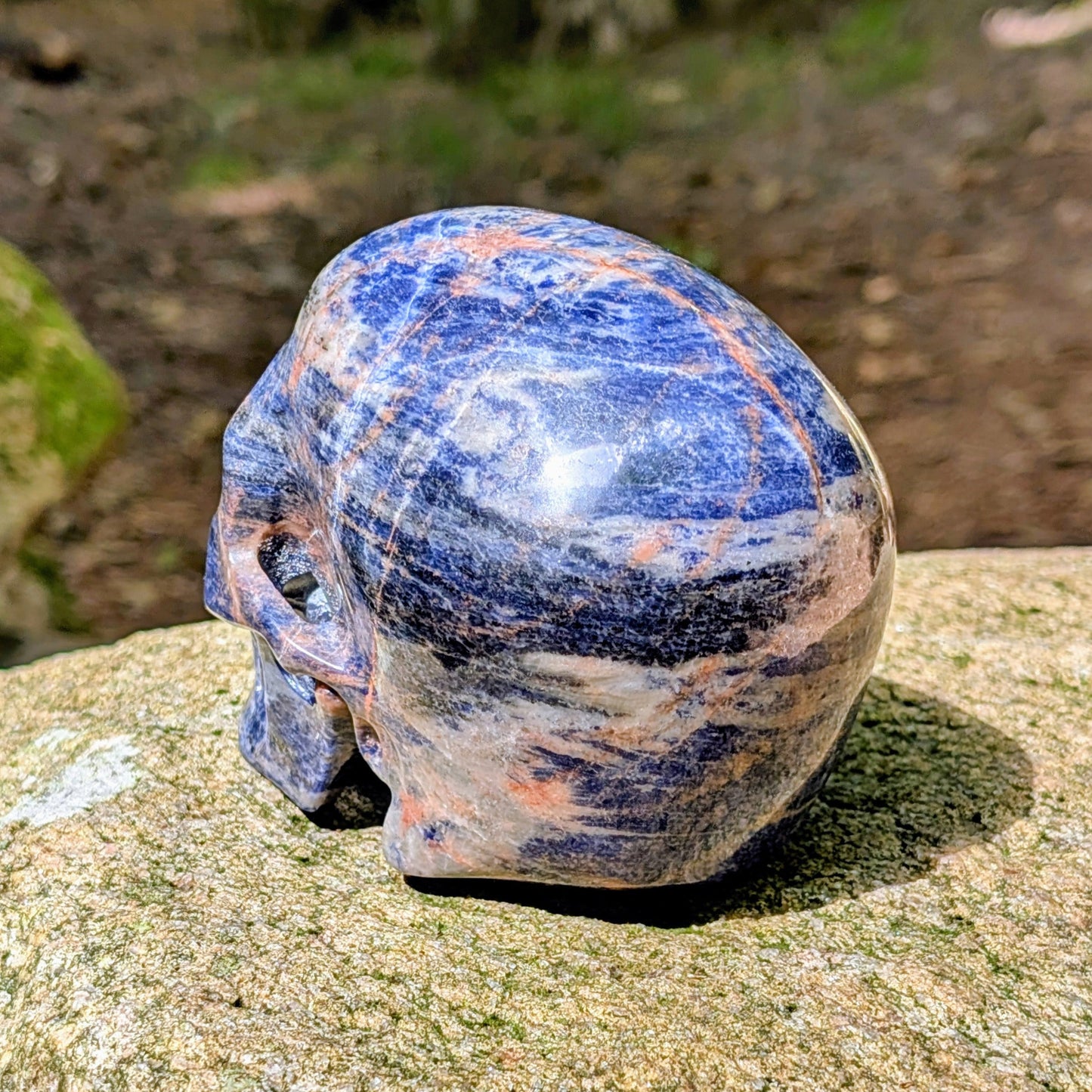 Kristallschädel "Himmelsweiser" aus Sodalith mit blau-weißer Maserung und orange-braunen Adern.
