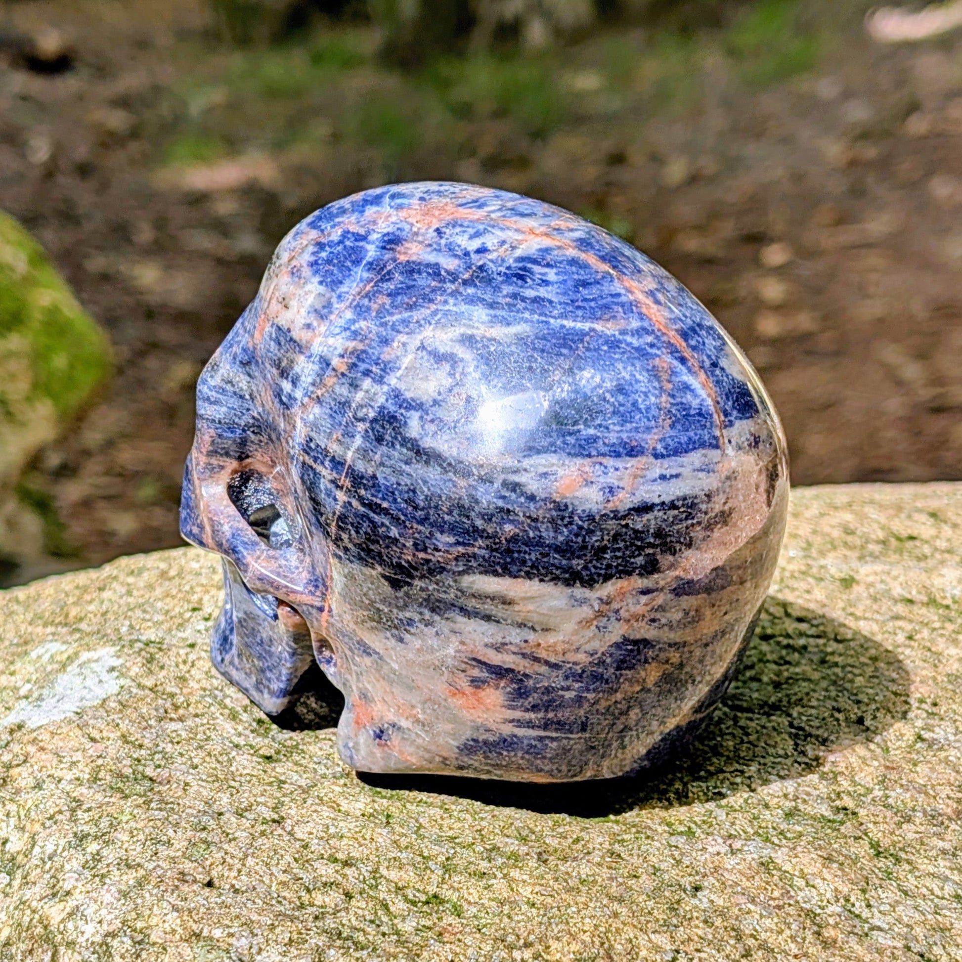 Kristallschädel "Himmelsweiser" aus Sodalith mit blau-weißer Maserung und orange-braunen Adern.