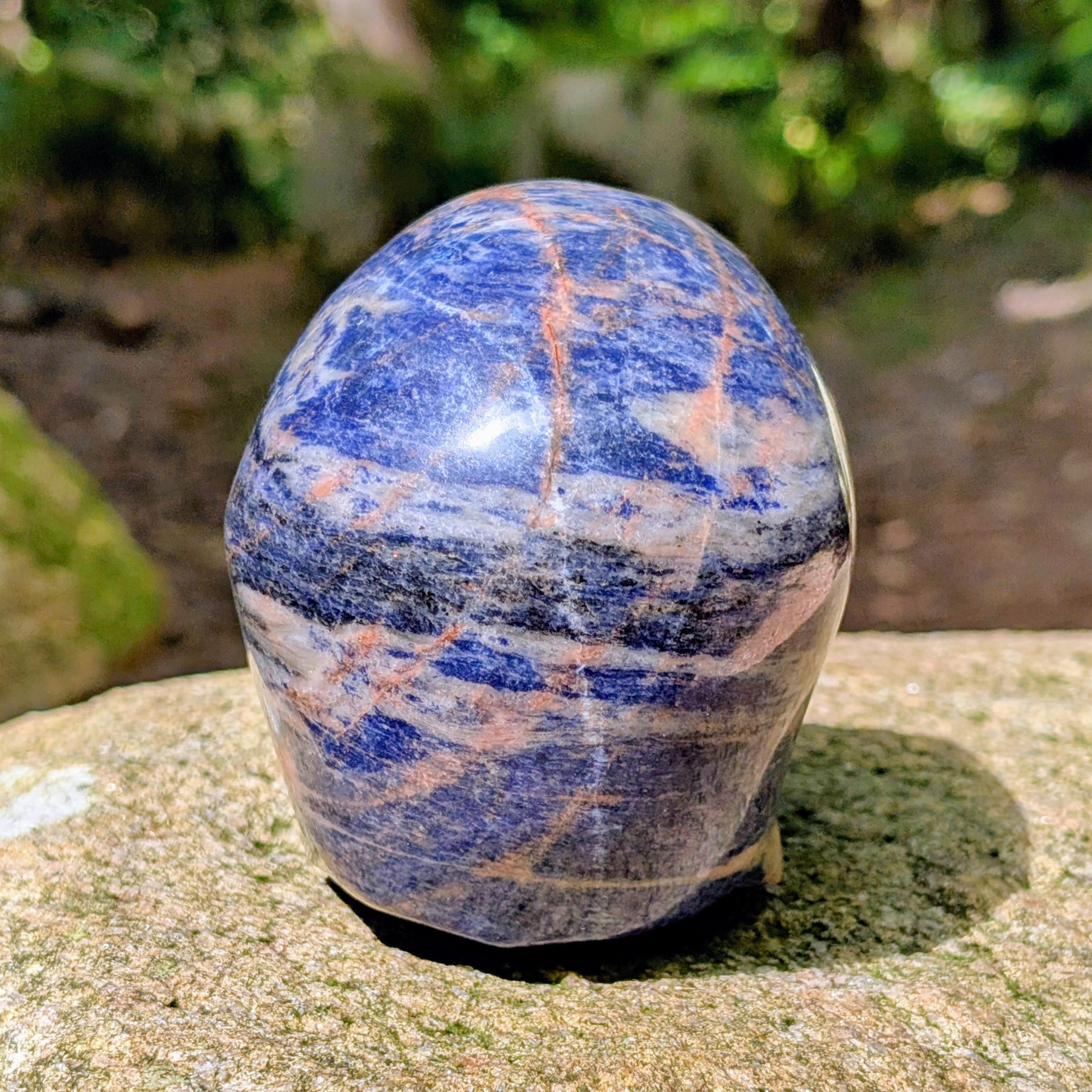 Kristallschädel "Himmelsweiser" aus Sodalith mit blau-weißer Maserung und orange-braunen Adern.