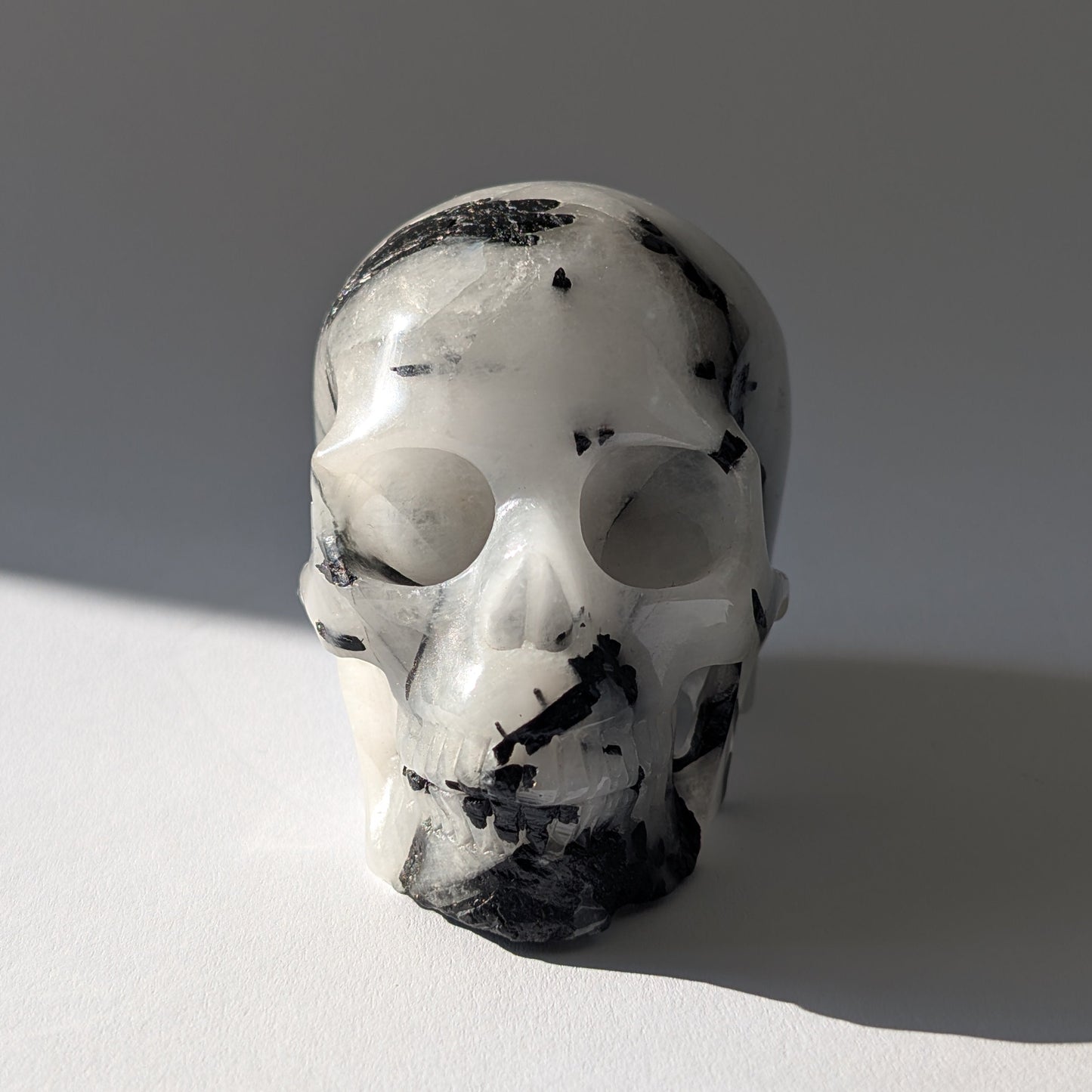 Kristallschädel "Hokan" (436g) aus klarem Quarz mit schwarzen Turmalin-Nadeln.