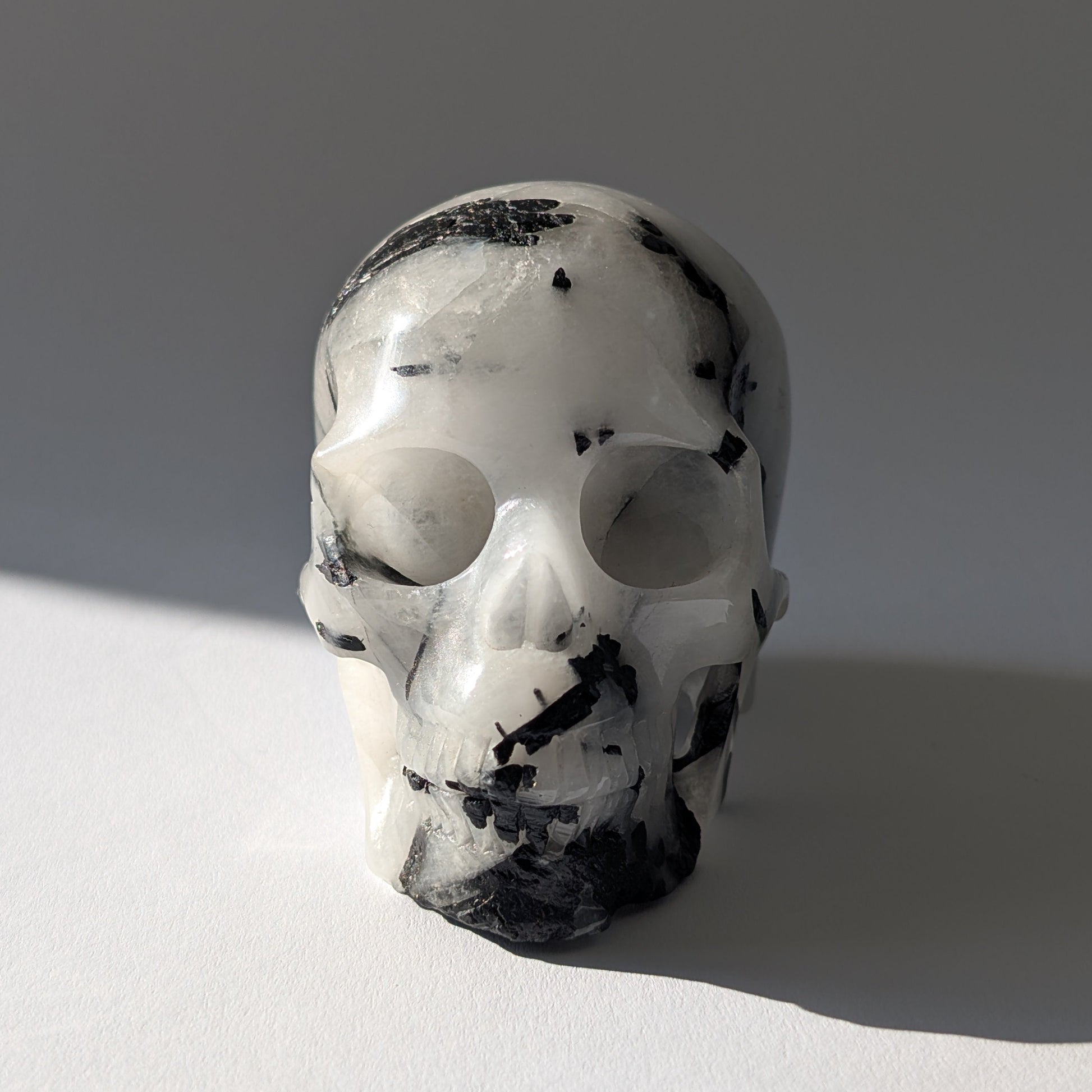Kristallschädel "Hokan" (436g) aus klarem Quarz mit schwarzen Turmalin-Nadeln.