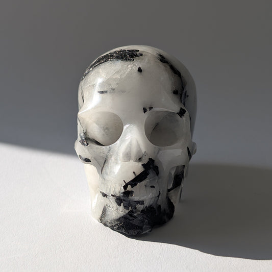 Kristallschädel "Hokan" (436g) aus klarem Quarz mit schwarzen Turmalin-Nadeln.