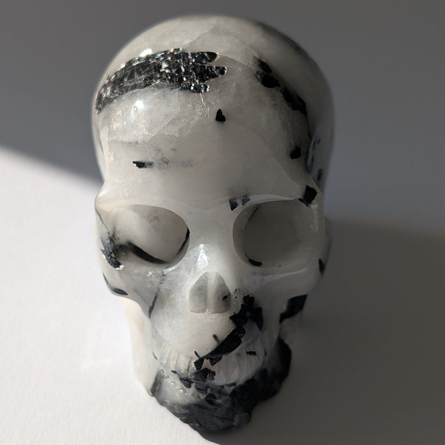 Kristallschädel "Hokan" (436g) aus klarem Quarz mit schwarzen Turmalin-Nadeln.