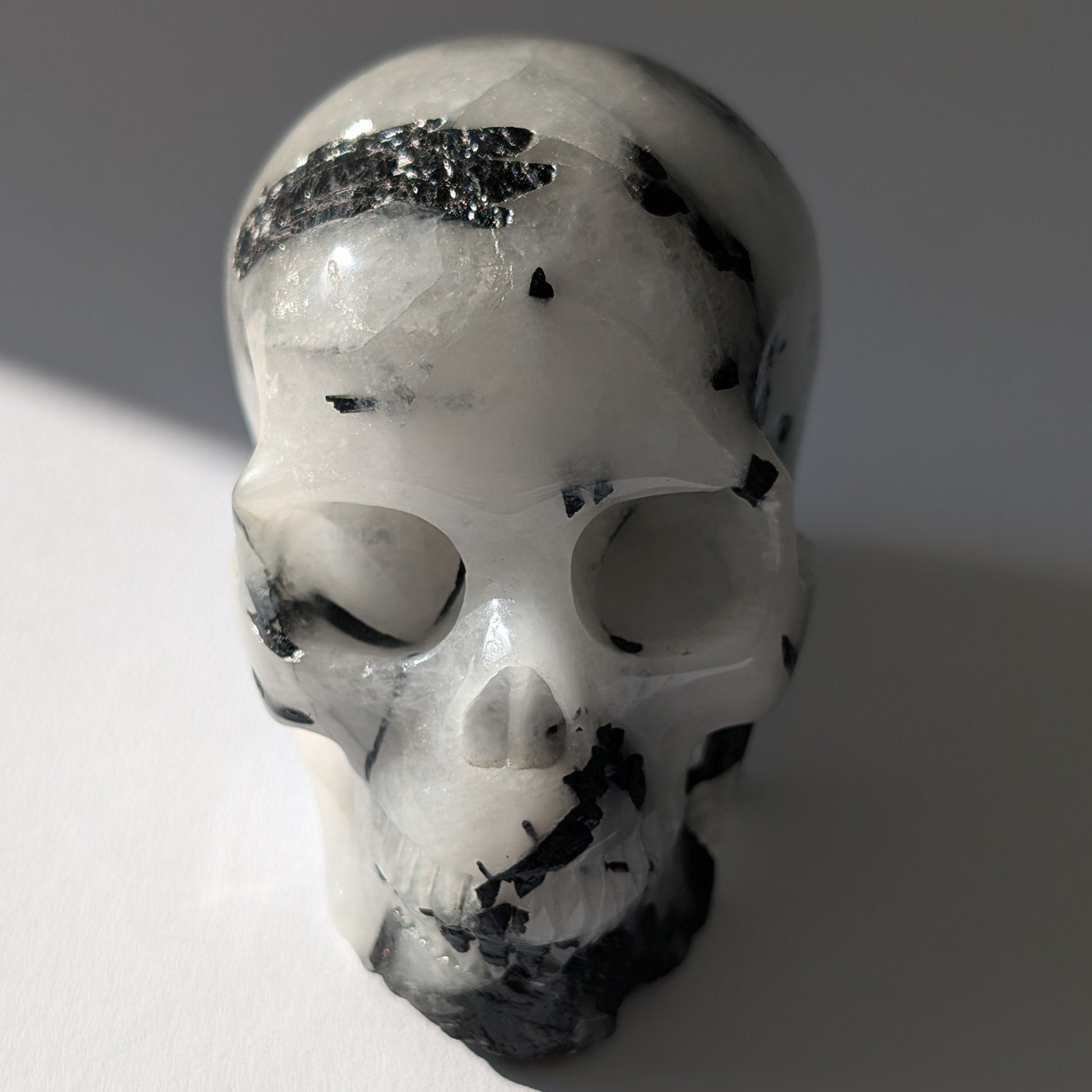 Kristallschädel "Hokan" (436g) aus klarem Quarz mit schwarzen Turmalin-Nadeln.