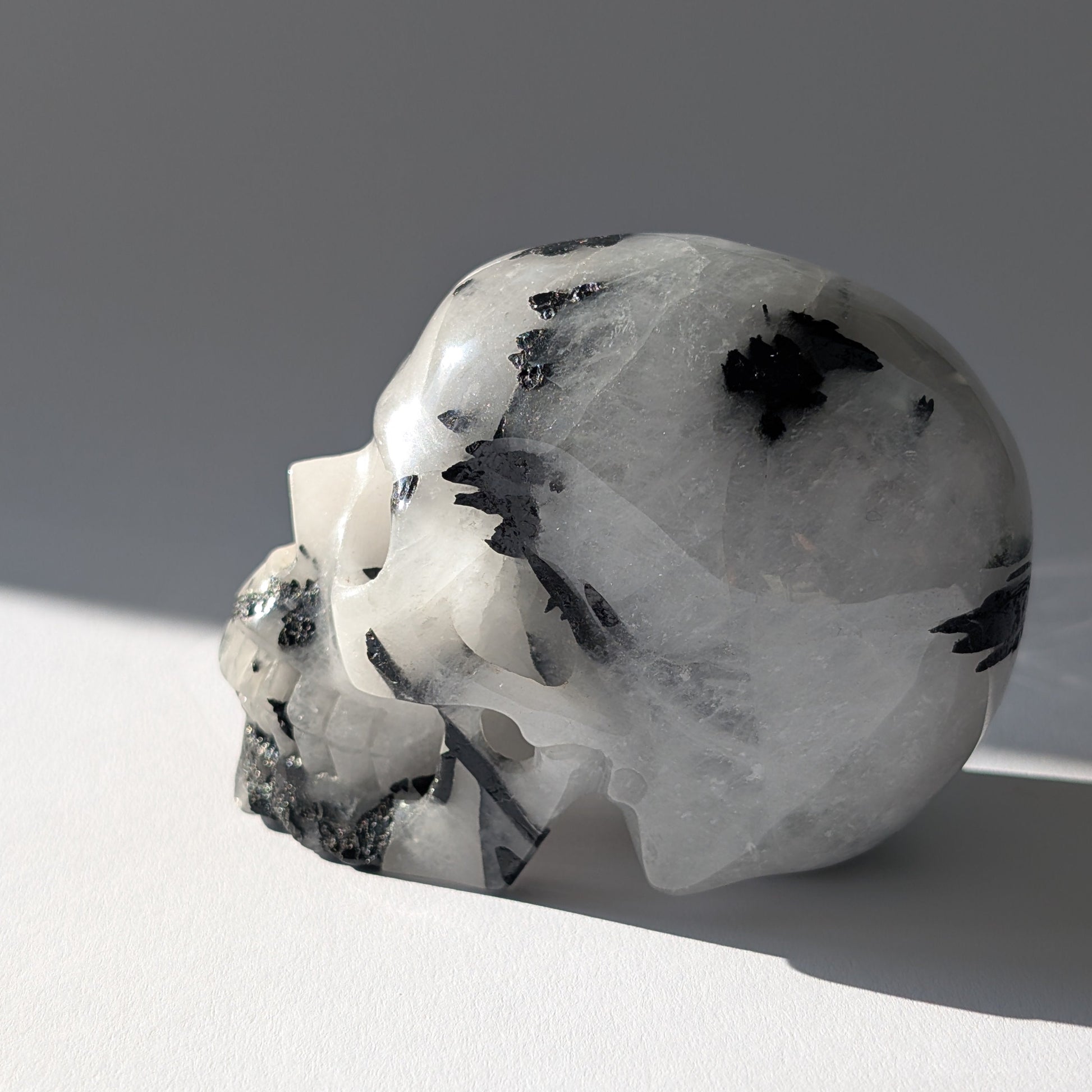 Kristallschädel "Hokan" (436g) aus klarem Quarz mit schwarzen Turmalin-Nadeln.