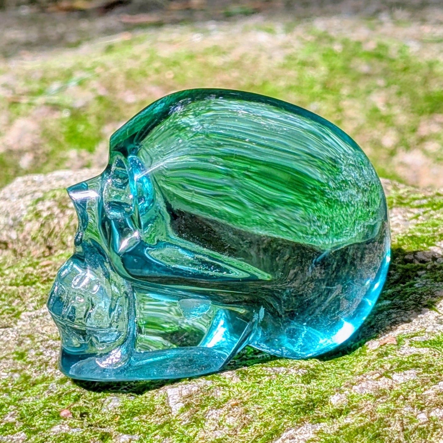 Kristallschädel "Ozeanseele" aus türkisfarbenem Quarzglas.