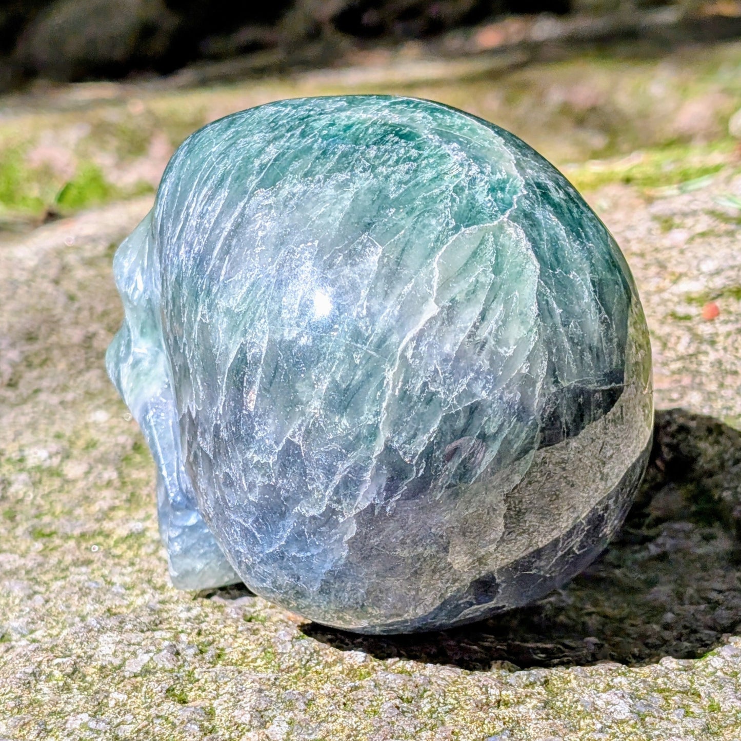 Kristallschädel "Regenbogenhüter" aus Regenbogenfluorit mit grünen, blauen und violetten Farbzonen.