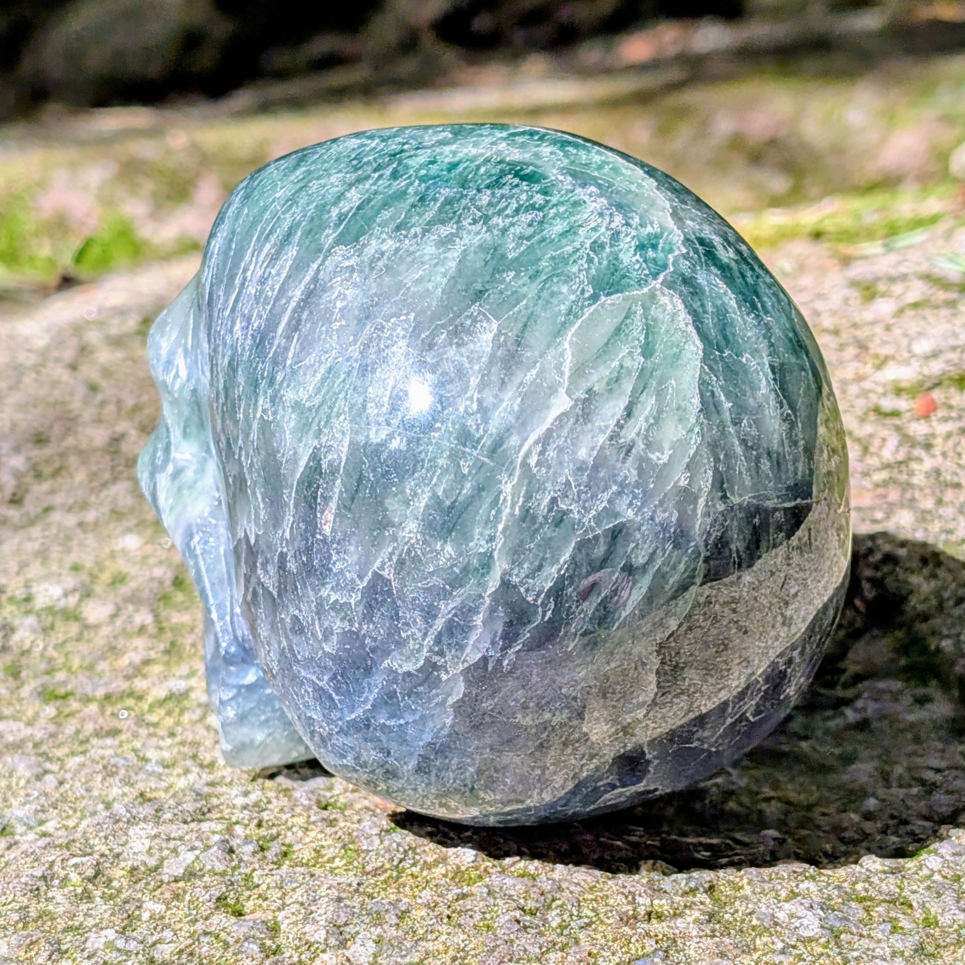 Kristallschädel "Regenbogenhüter" aus Regenbogenfluorit mit grünen, blauen und violetten Farbzonen.