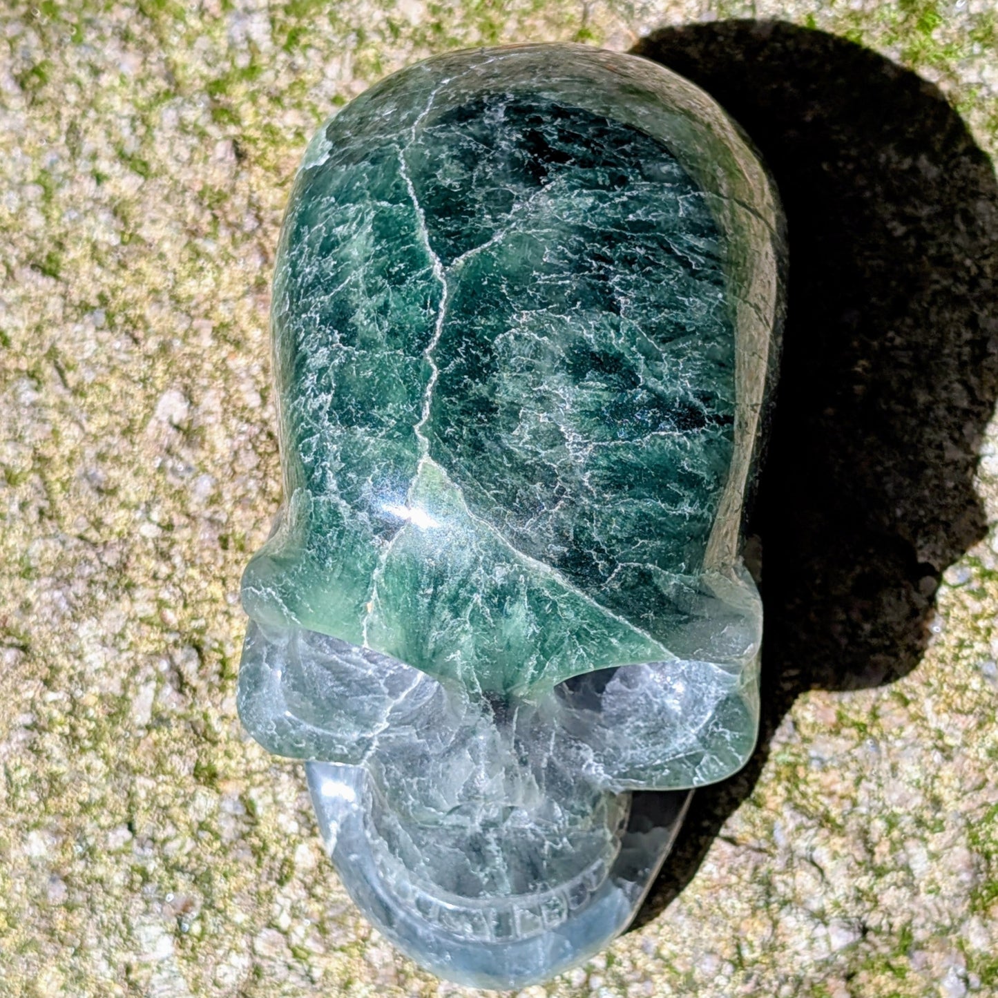 Kristallschädel "Regenbogenhüter" aus Regenbogenfluorit mit grünen, blauen und violetten Farbzonen.