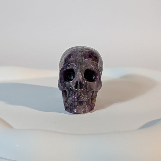 Kristallschädel Sartarius aus violettem Amethyst mit lichtdurchlässigen Zonen und sanften weißen Quarz-Strukturen.