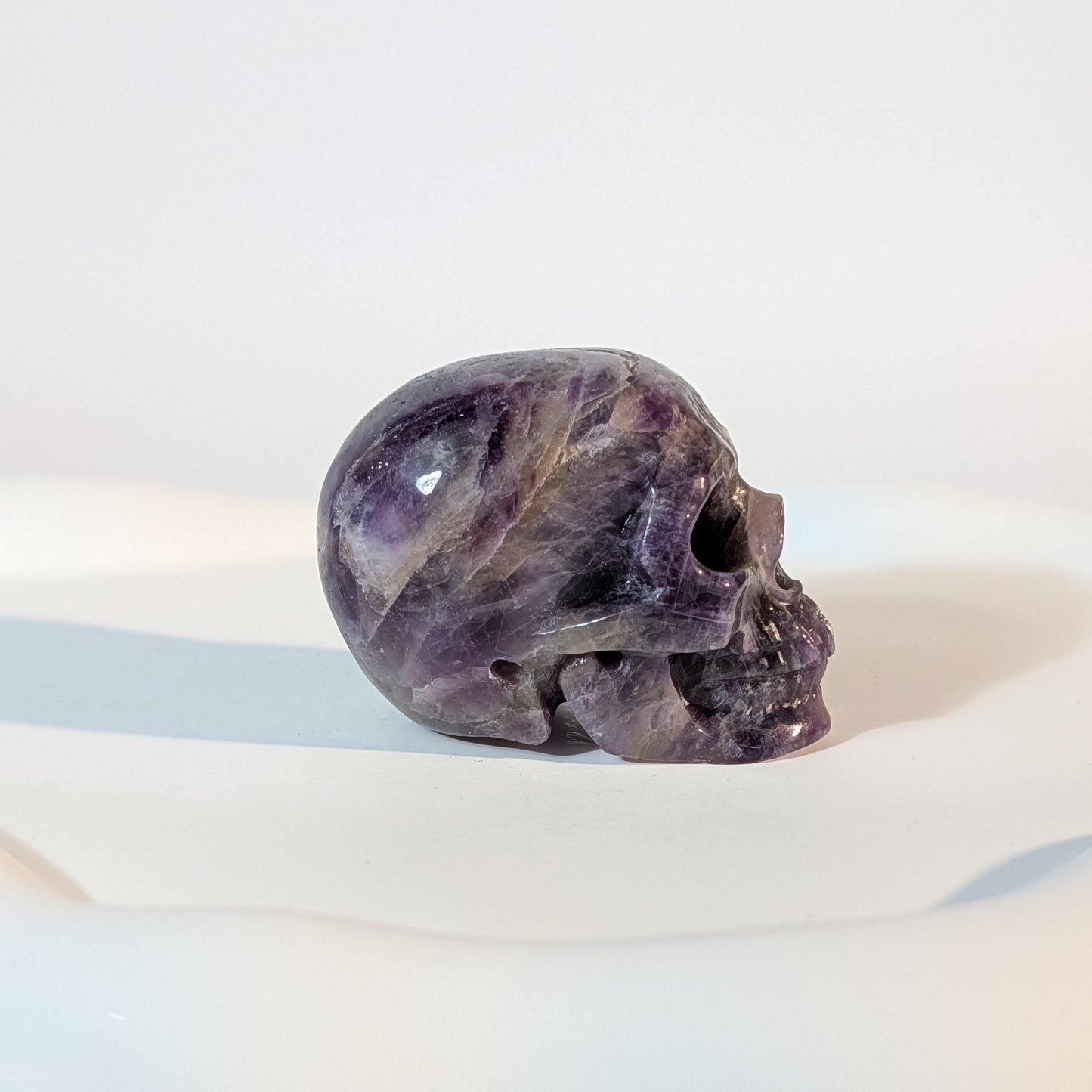 Kristallschädel Sartarius aus violettem Amethyst mit lichtdurchlässigen Zonen und sanften weißen Quarz-Strukturen.