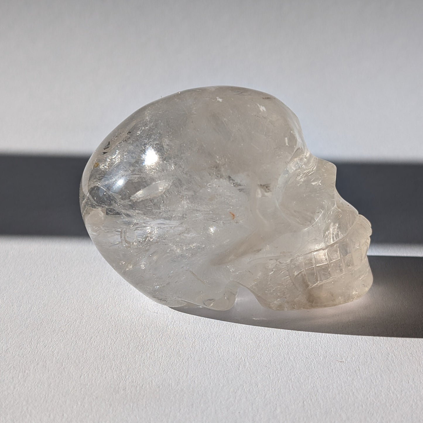 Kristallschädel "Sayir" (342g) aus klarem Bergkristall mit inneren Lichtreflexionen.