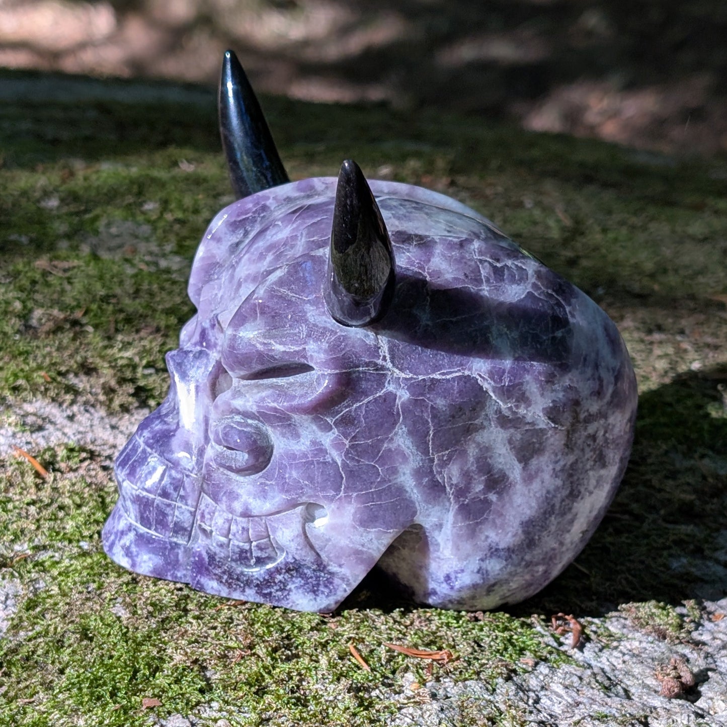 Kristallschädel "Schattenfürst" aus Amethyst mit schwarzen Obsidian-Hörnern.