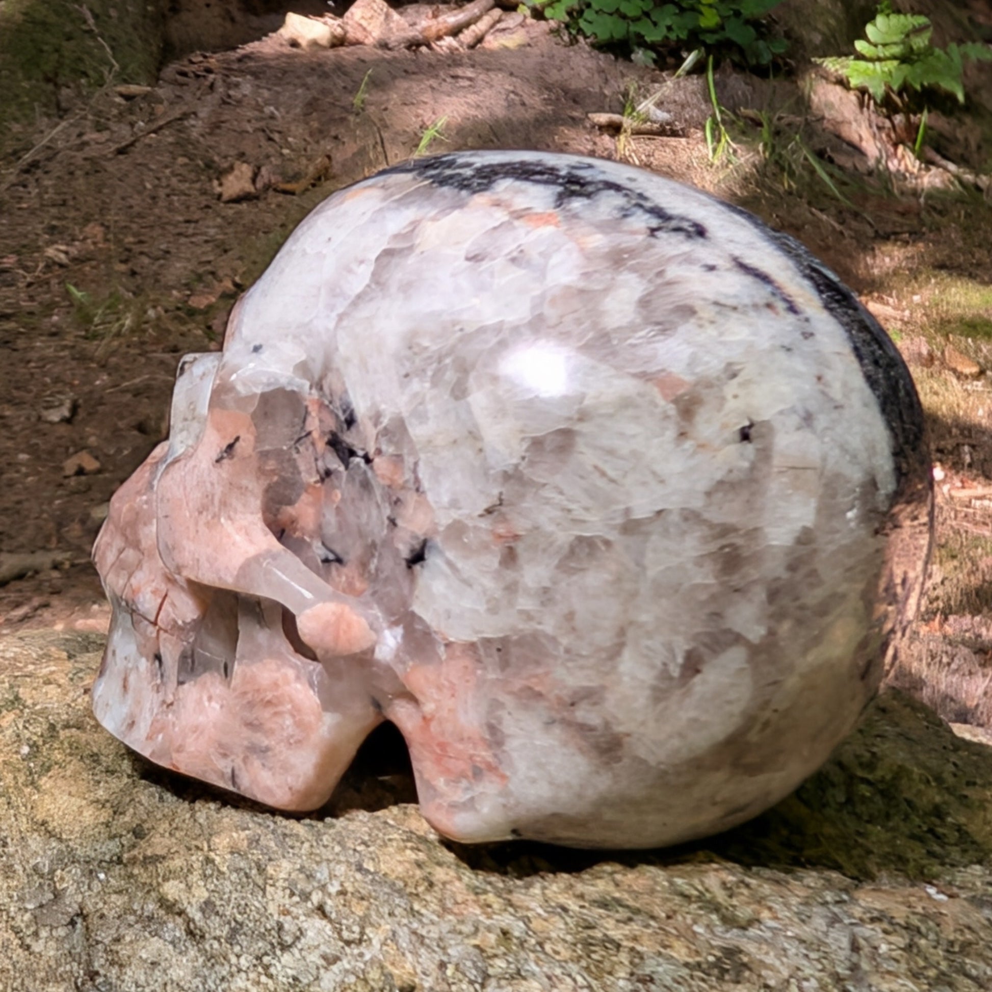 Kristallschädel "Sternenstaub" aus Granit mit schwarzer, weißer und rosafarbener Maserung.