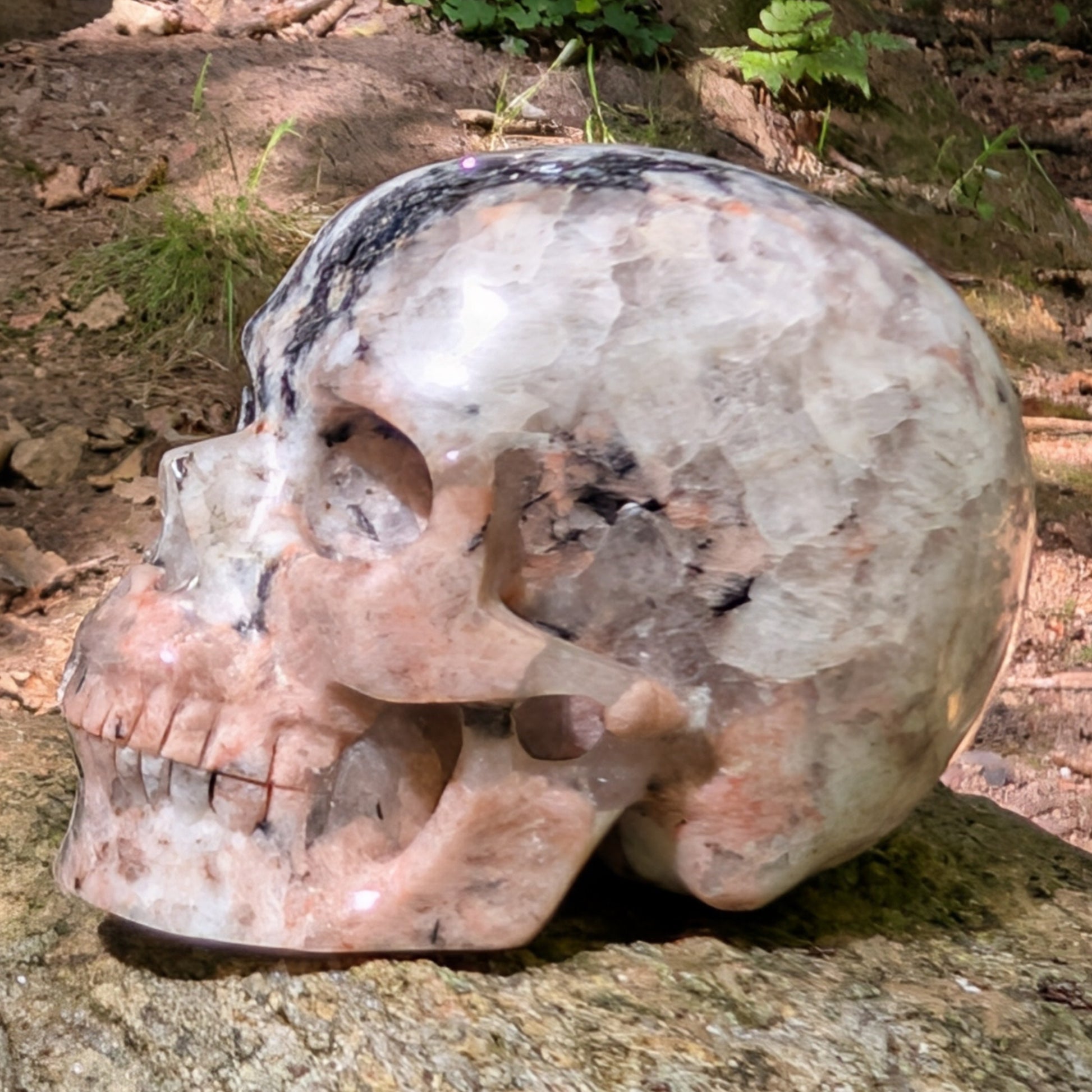 Kristallschädel "Sternenstaub" aus Granit mit schwarzer, weißer und rosafarbener Maserung.