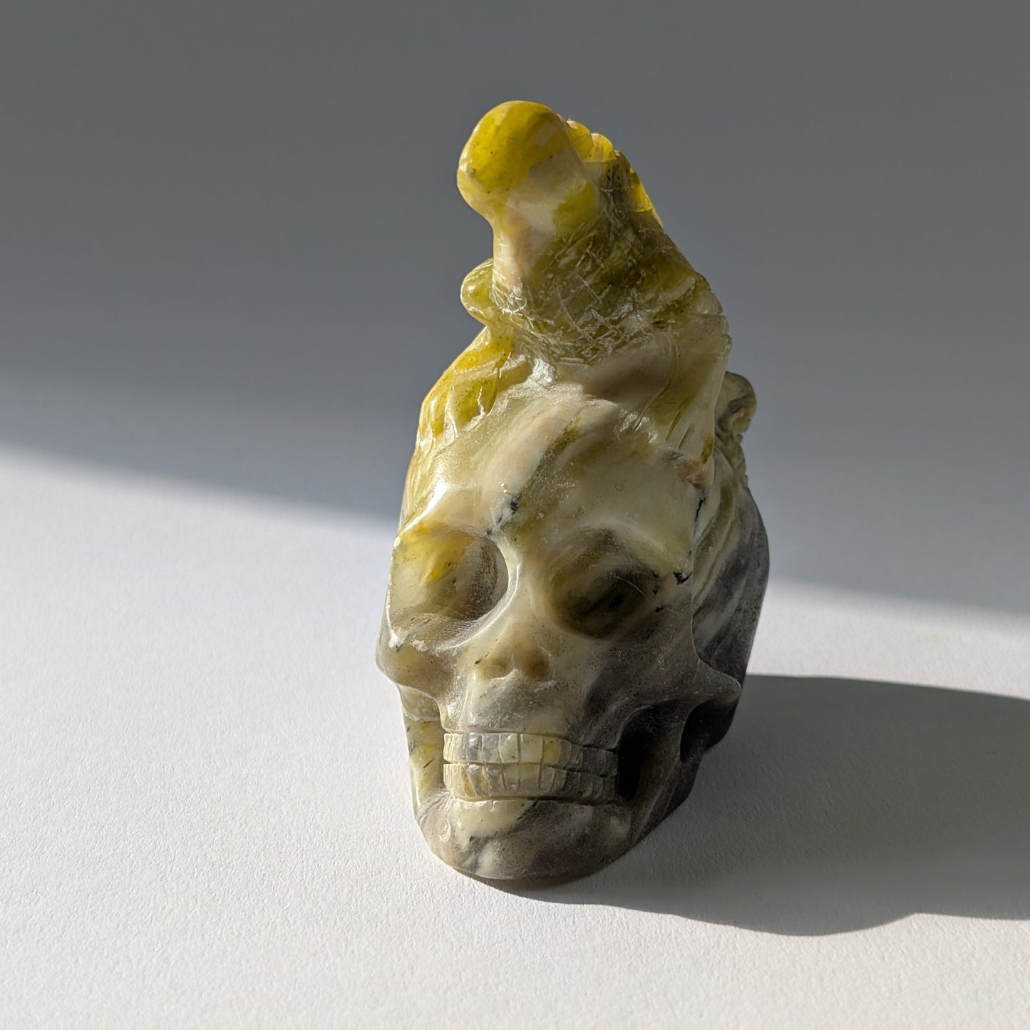 Kristallschädel "Theuth" (140g) aus Serpentin mit einer geschnitzten Eidechse auf dem Kopf.