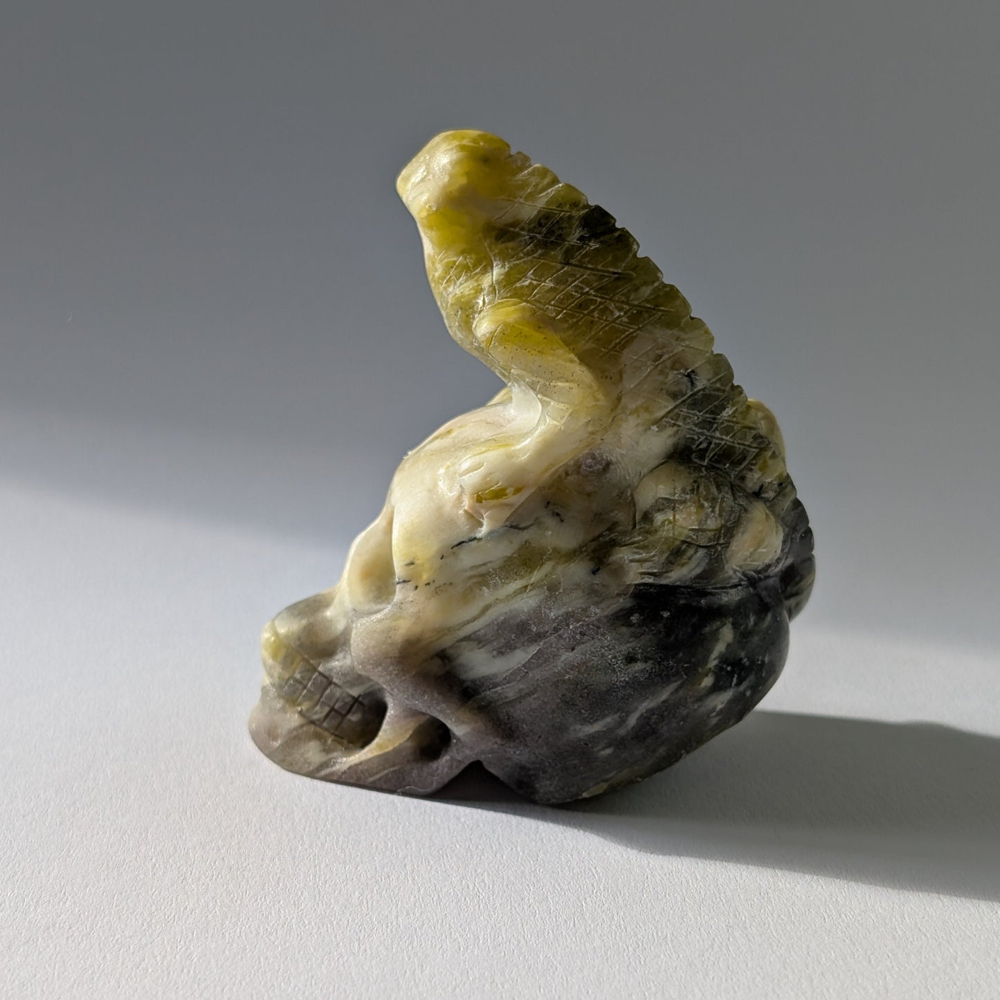 Kristallschädel "Theuth" (140g) aus Serpentin mit einer geschnitzten Eidechse auf dem Kopf.