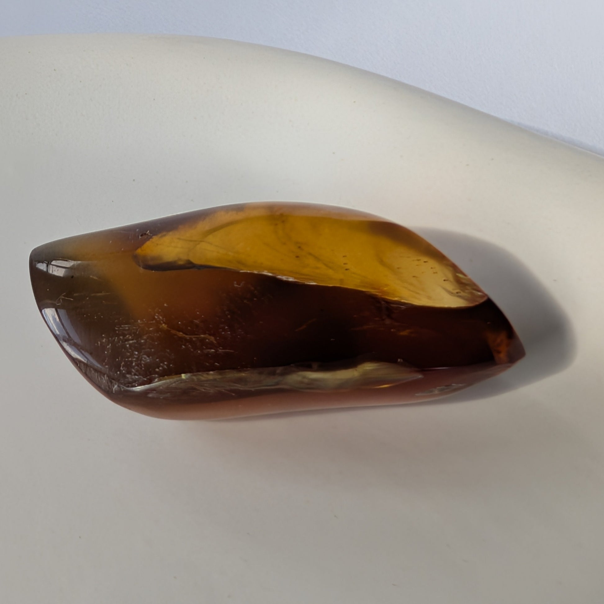 Kunstvoll geschliffener Bicolor-Bernstein 'Die Flamme der Vorzeit' in eleganter Flammenform, der von tiefrot zu gold leuchtet.