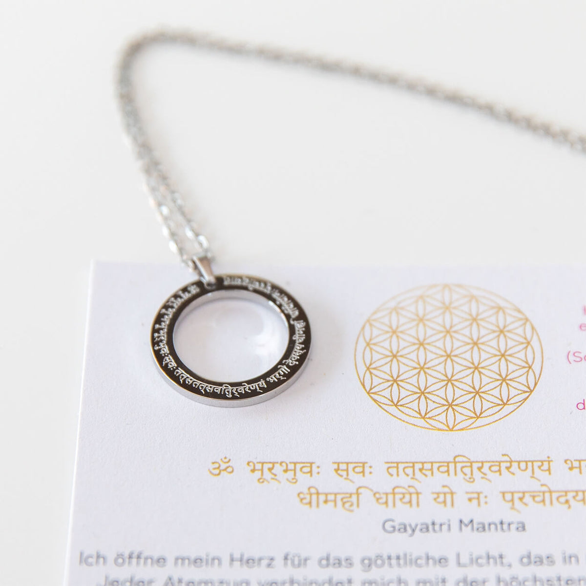 Gayatri Mantra Kette in Silber mit rundem Ring-Anhänger neben einer Karte