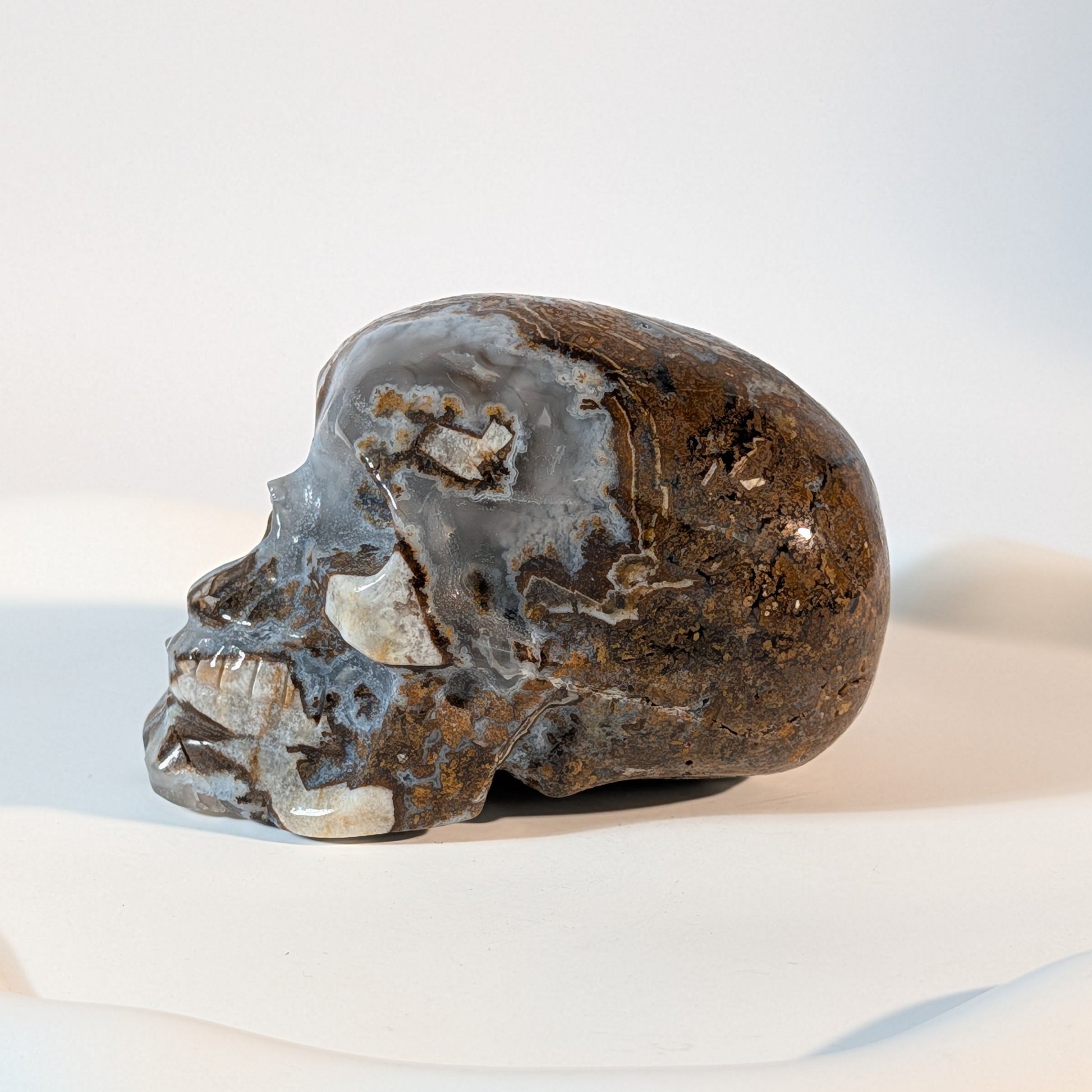 Massiver Kristallschädel Mumugg aus erdfarbenem Quarz mit tiefen, offenen Kristallhöhlen und zerrissener Gesteinsmatrix.
