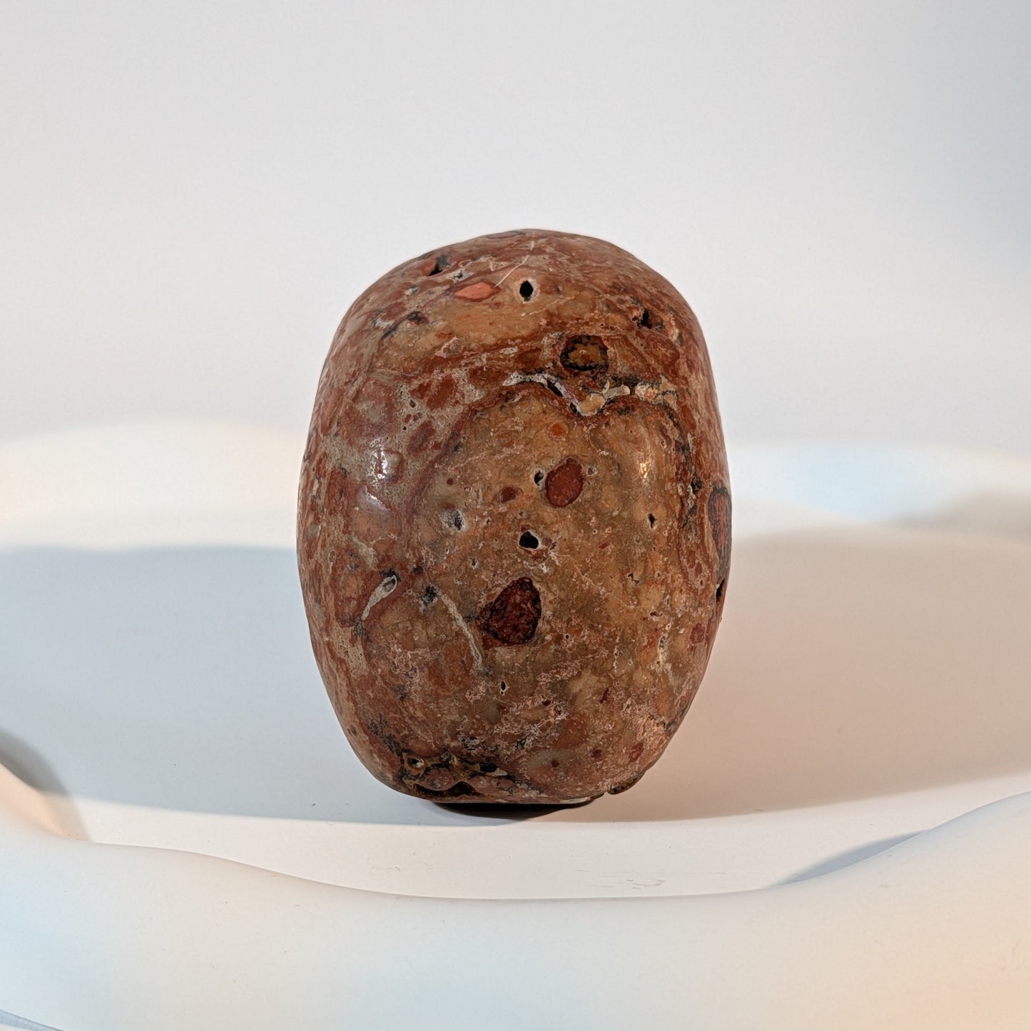Massiver Kristallschädel Sidahan aus Rhyolith mit blutroter und rostbrauner, von Kratern und dunklen Pocken durchzogener Gesteinsmatrix.