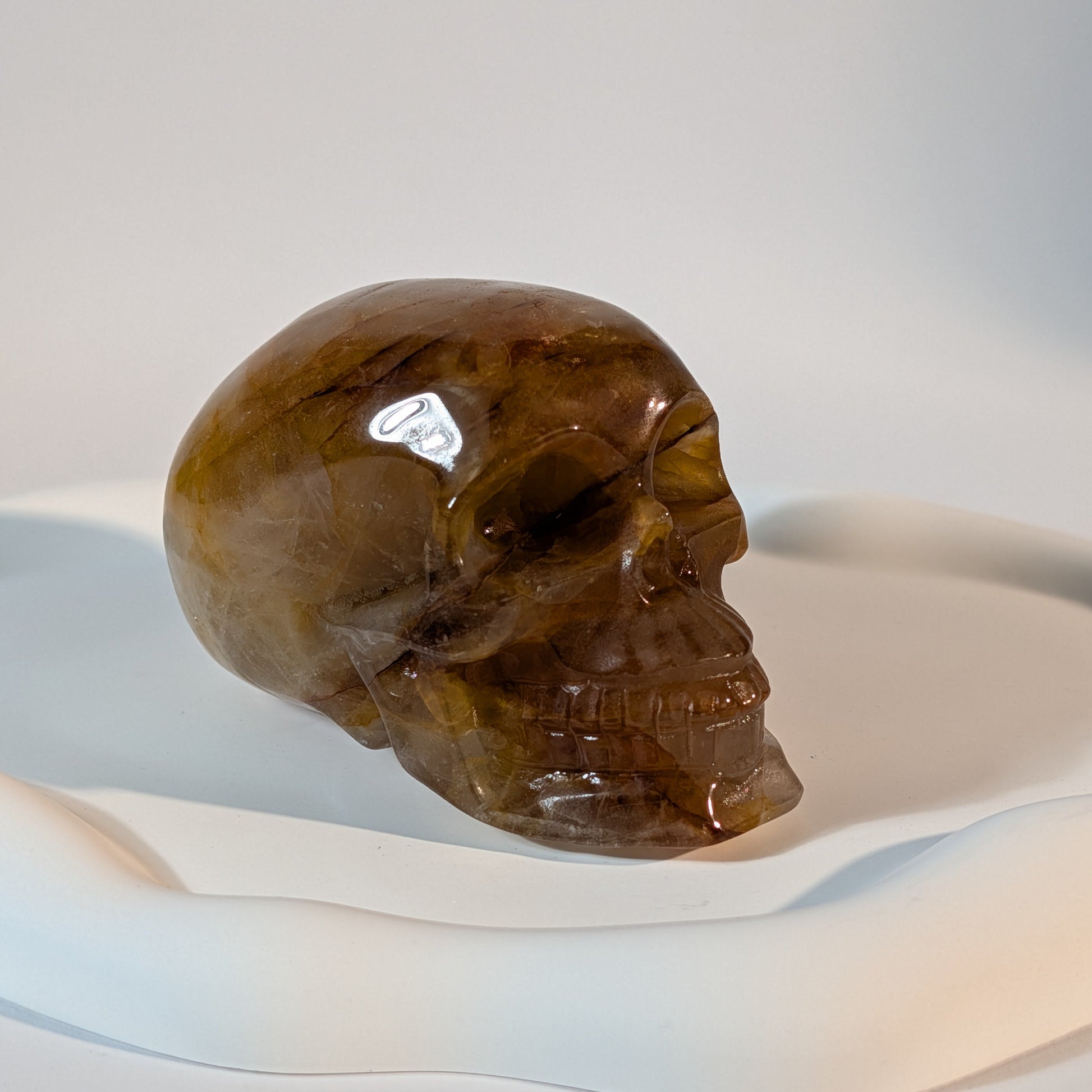 Massiver, bernsteinfarbener Kristallschädel Muirne aus Quarz mit tiefen, dunklen Rissen und rostigen Eiseneinschlüssen.